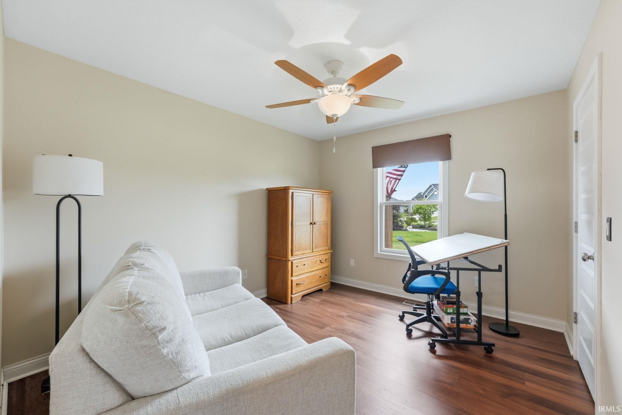 Spacious room featuring wood-finish flooring, a window with exterior views, and a ceiling fan