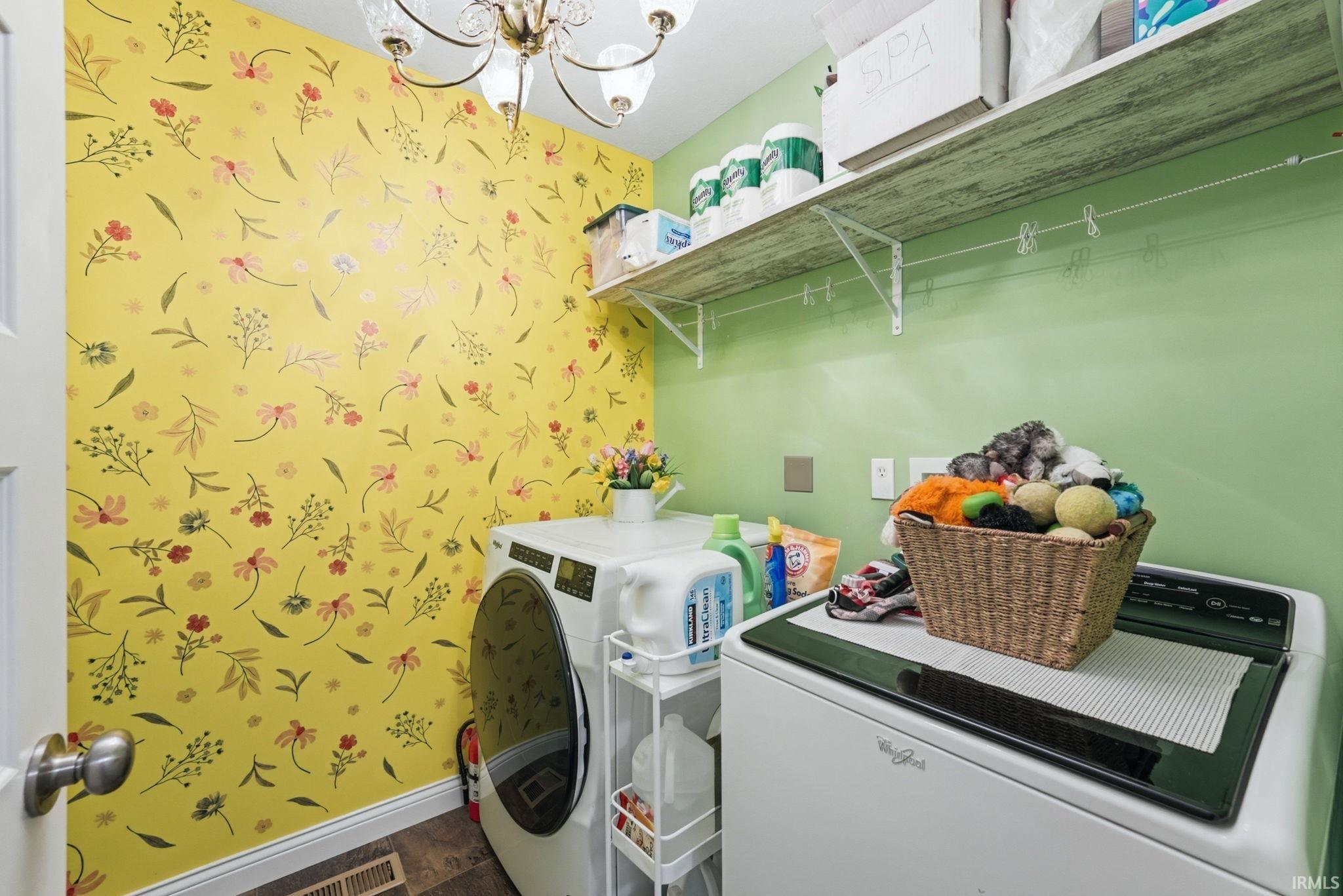 Dedicated laundry area featuring patterned wallpaper and wood-finish flooring