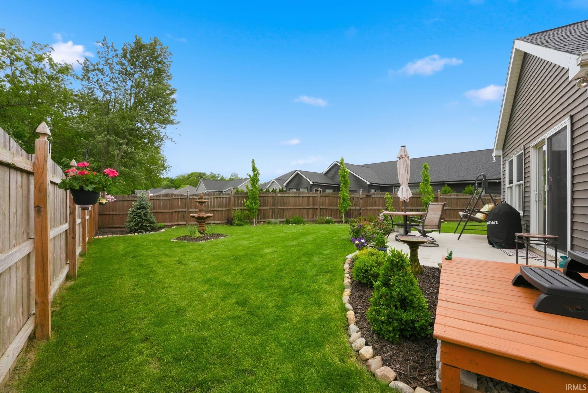 Expansive backyard featuring a wood privacy fence, a concrete patio, and a wood deck