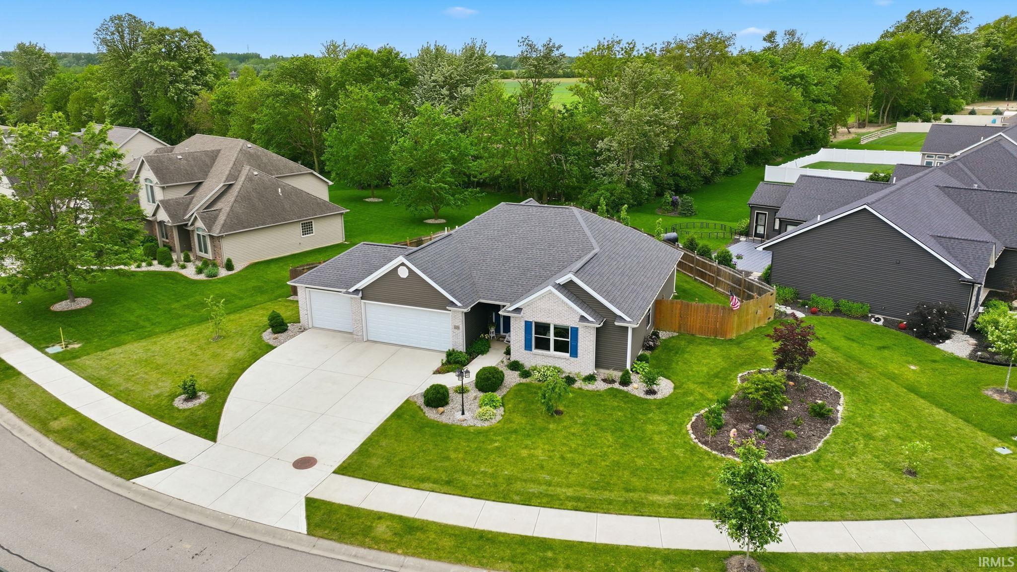 Contemporary ranch-style home featuring a two-car garage, concrete driveway, and a manicured lawn