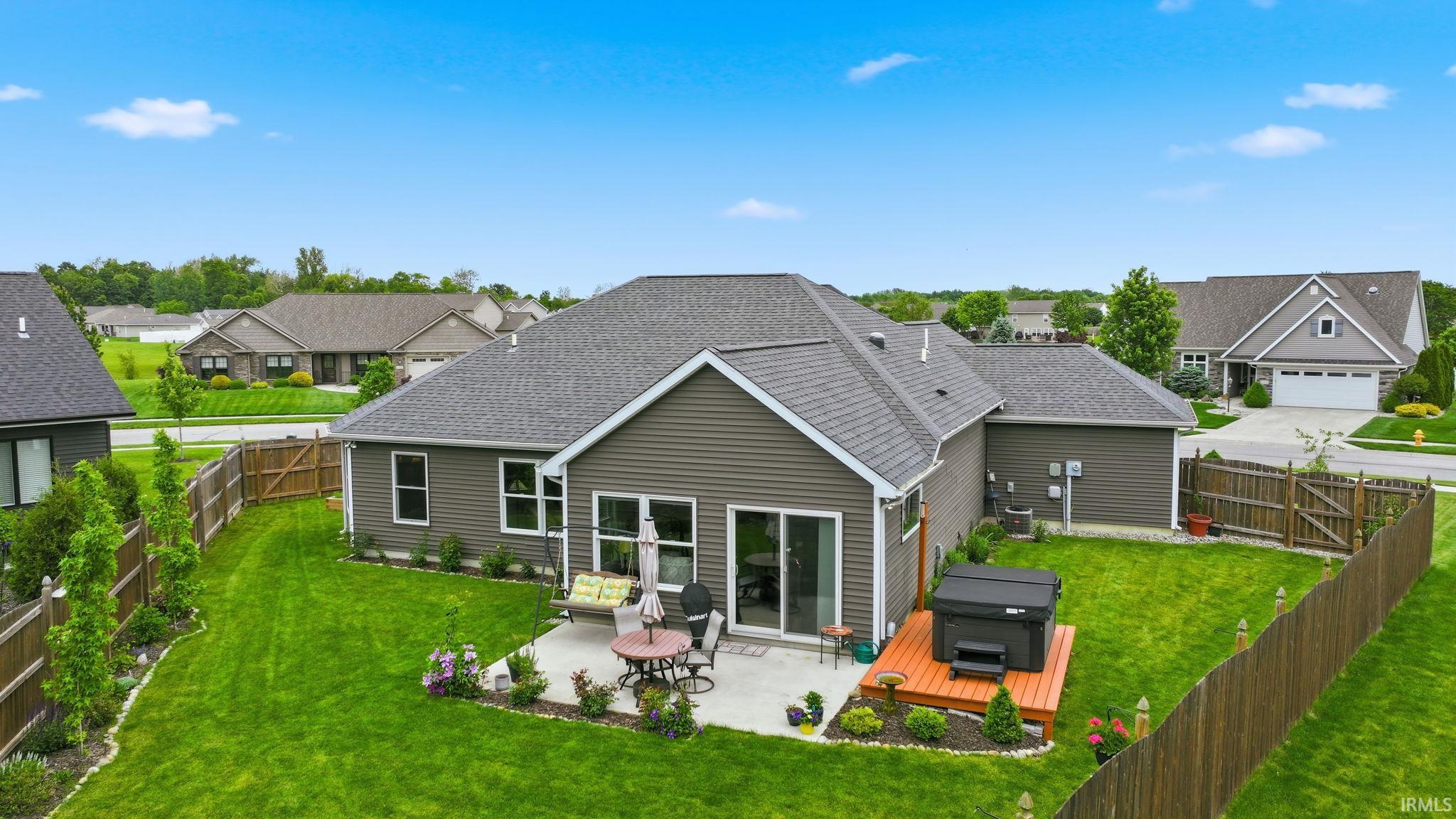 Expansive fenced backyard featuring a concrete patio, a private hot tub deck, and a manicured lawn