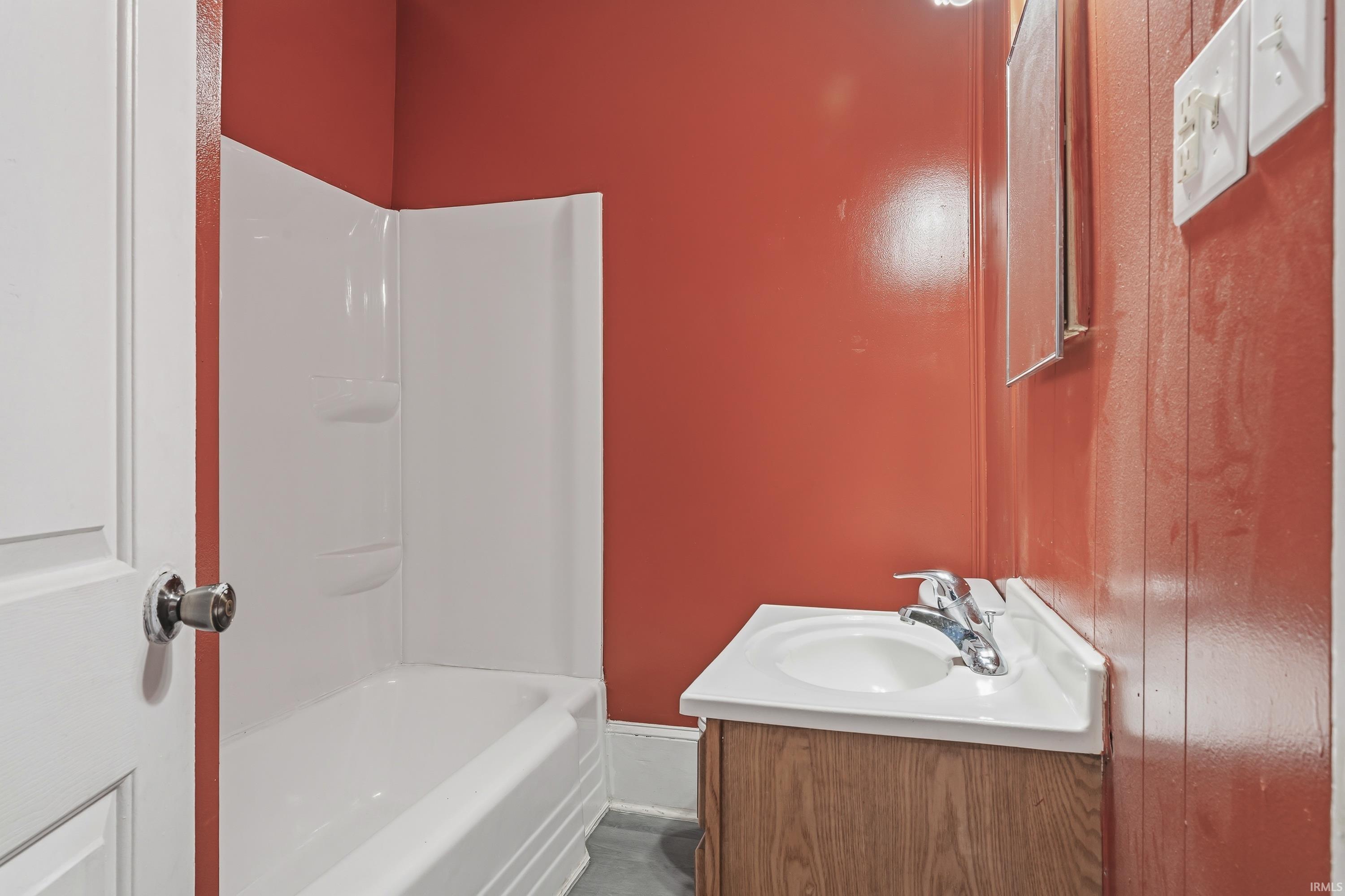 Bathroom featuring a white bathtub, wood-finish vanity with an integrated sink, and chrome faucet