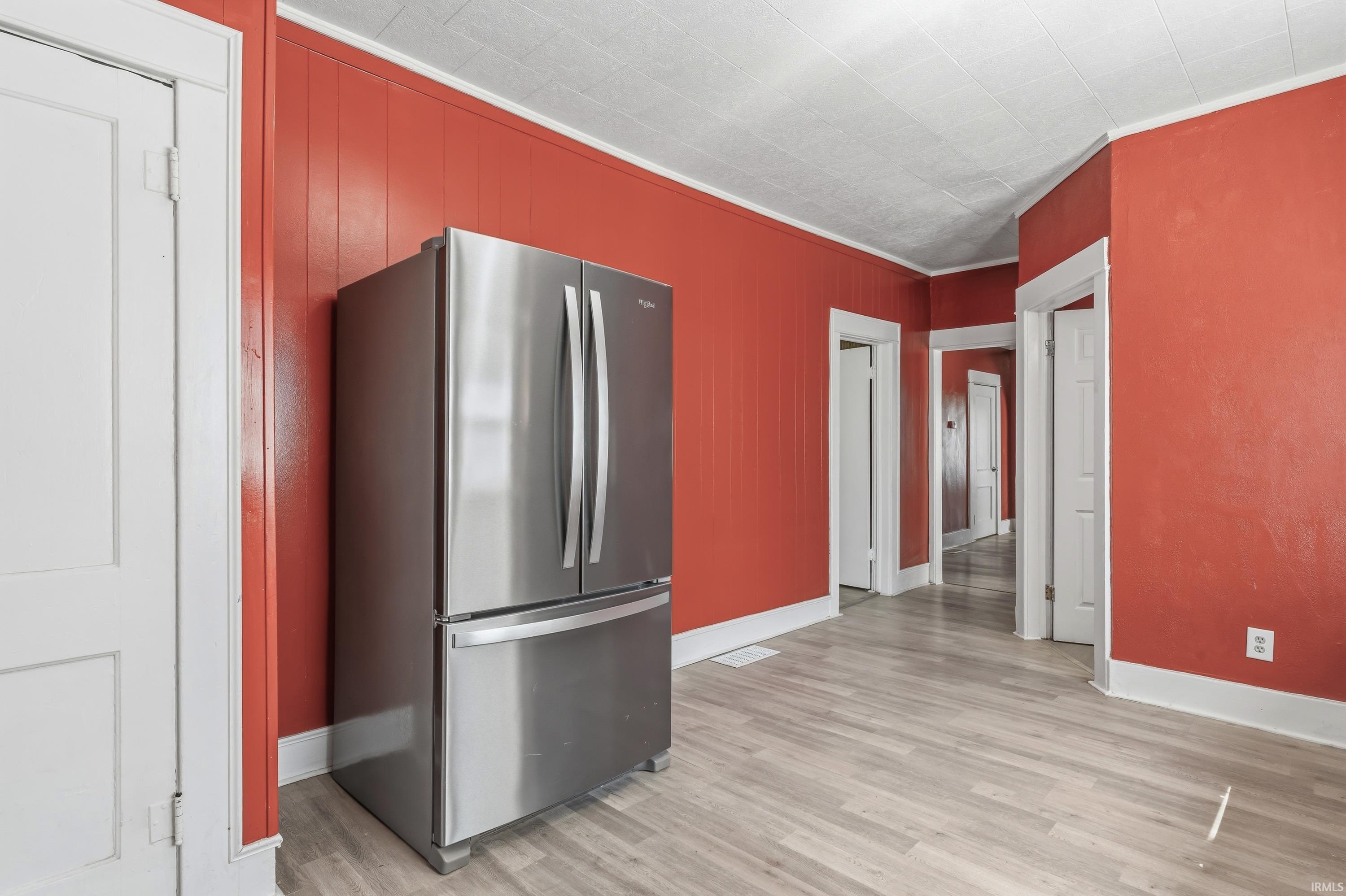 Stainless steel refrigerator within a room featuring red paneling and white trim