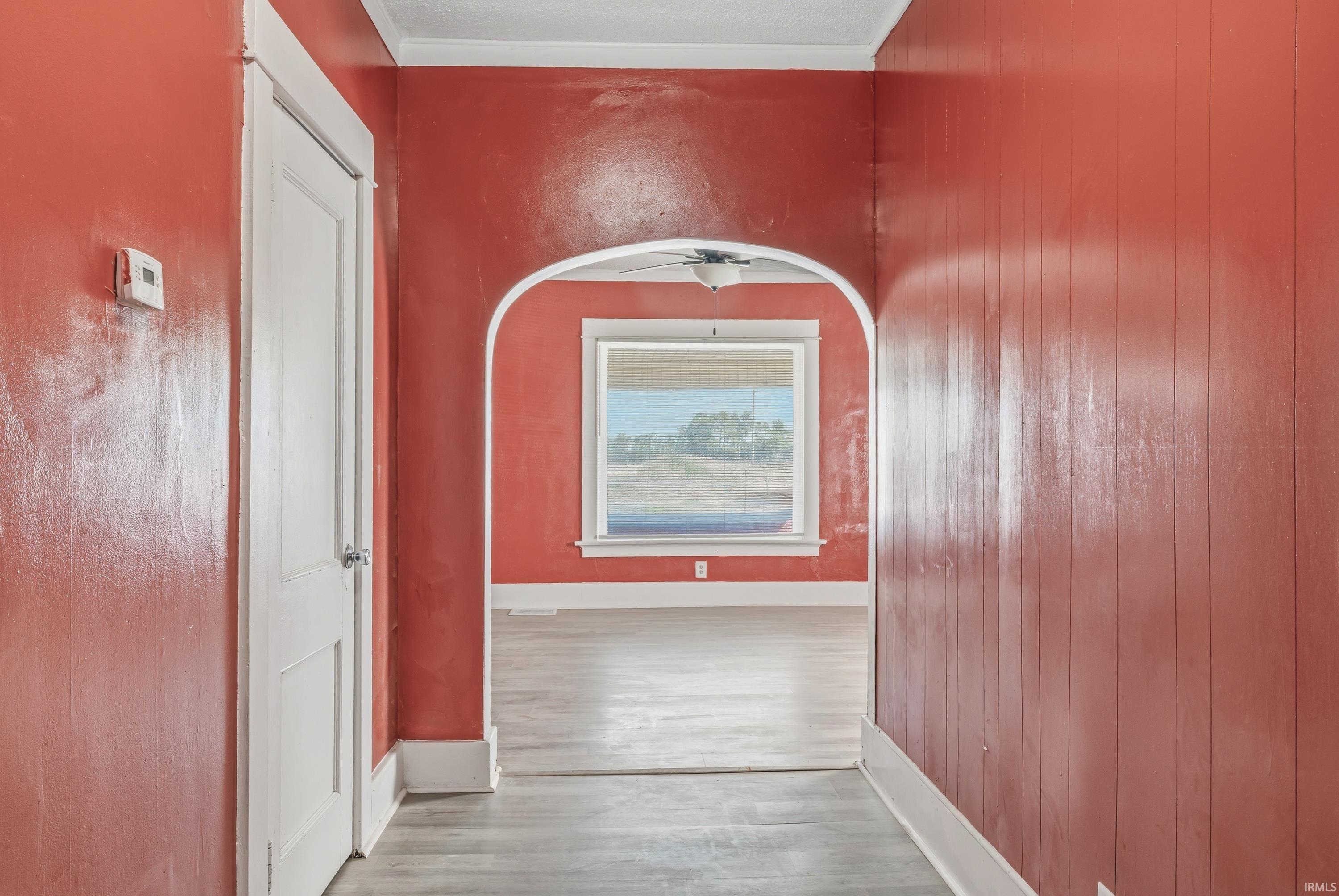 Archway entrance with white trim, leading into a room with a window featuring a natural landscape