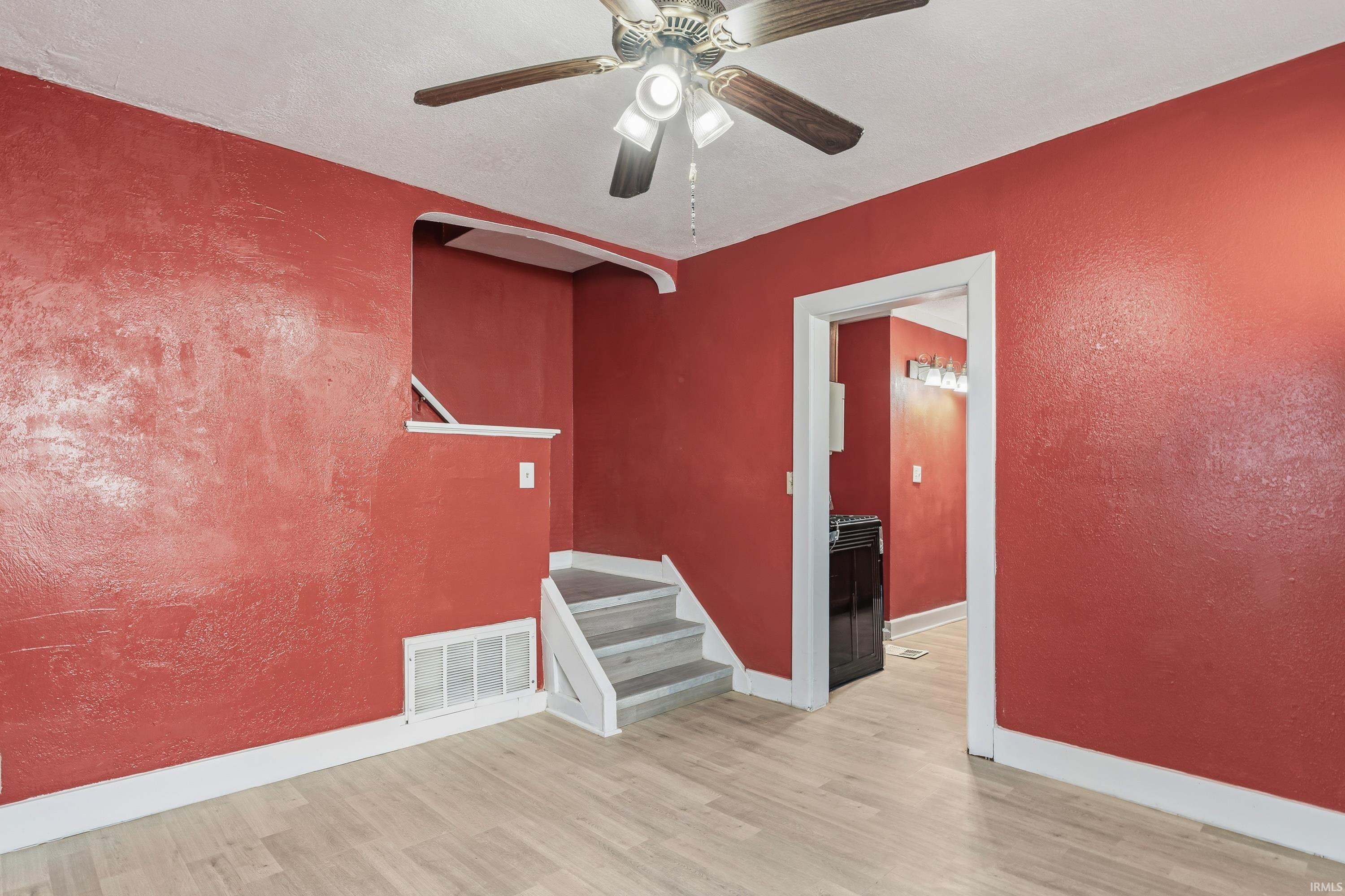 Interior space featuring wood-finish flooring, a ceiling fan with integrated lighting, and white trim throughout