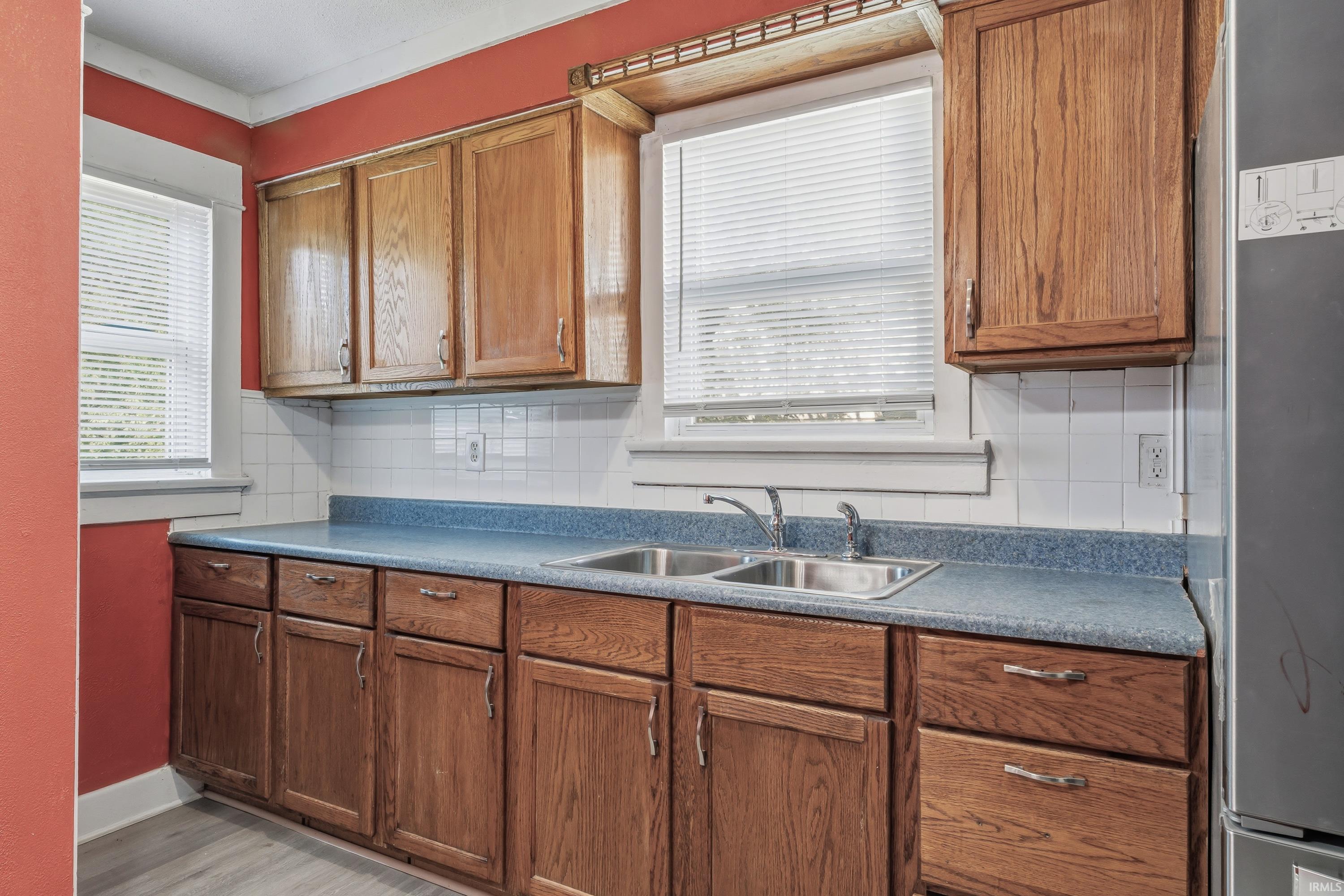 Kitchen featuring wood cabinetry, a double basin stainless steel sink, and blue countertops