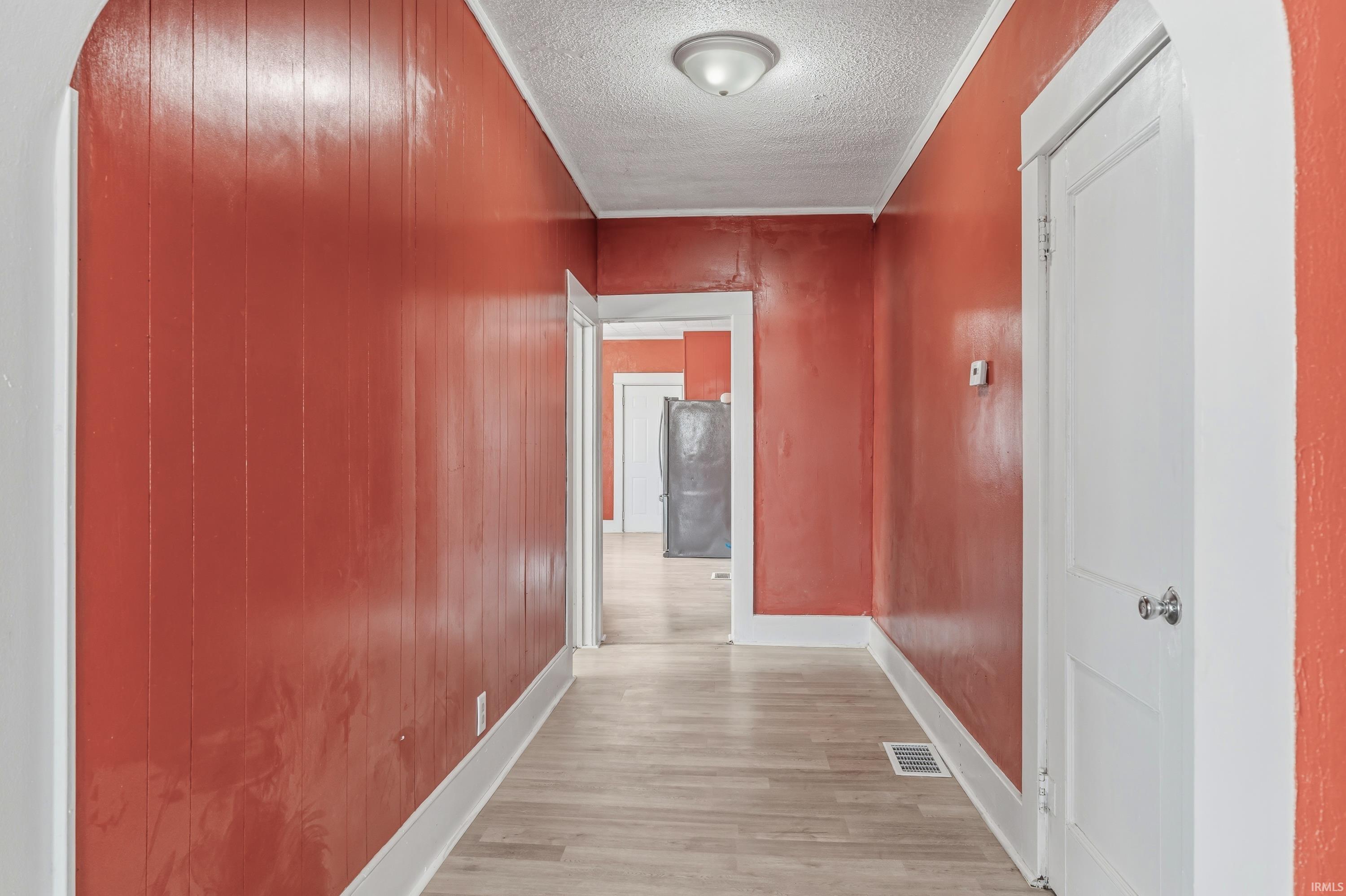 Hallway featuring wood-finish flooring and red paneling