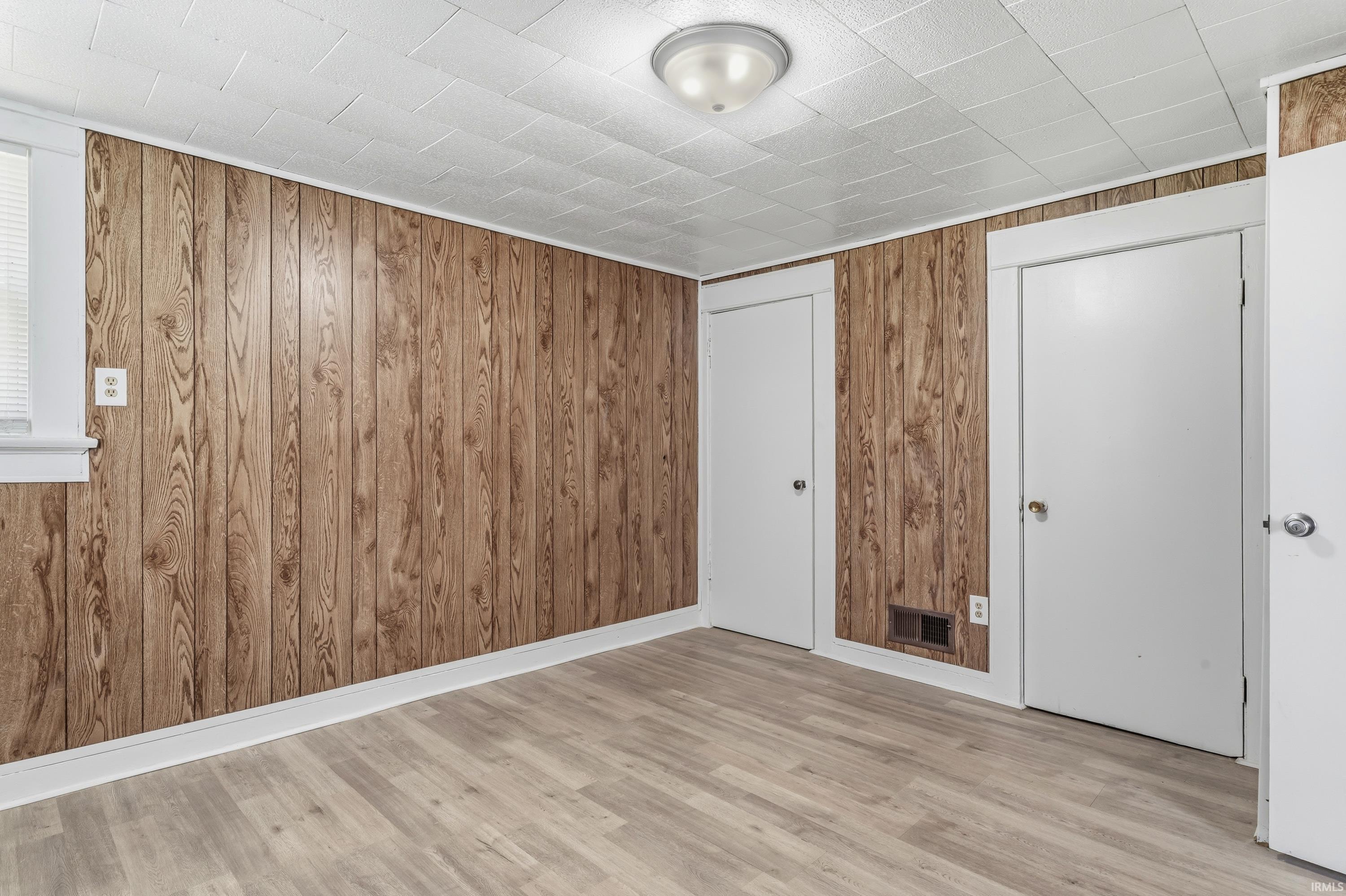 Room featuring wood-paneled walls and light wood-finish flooring