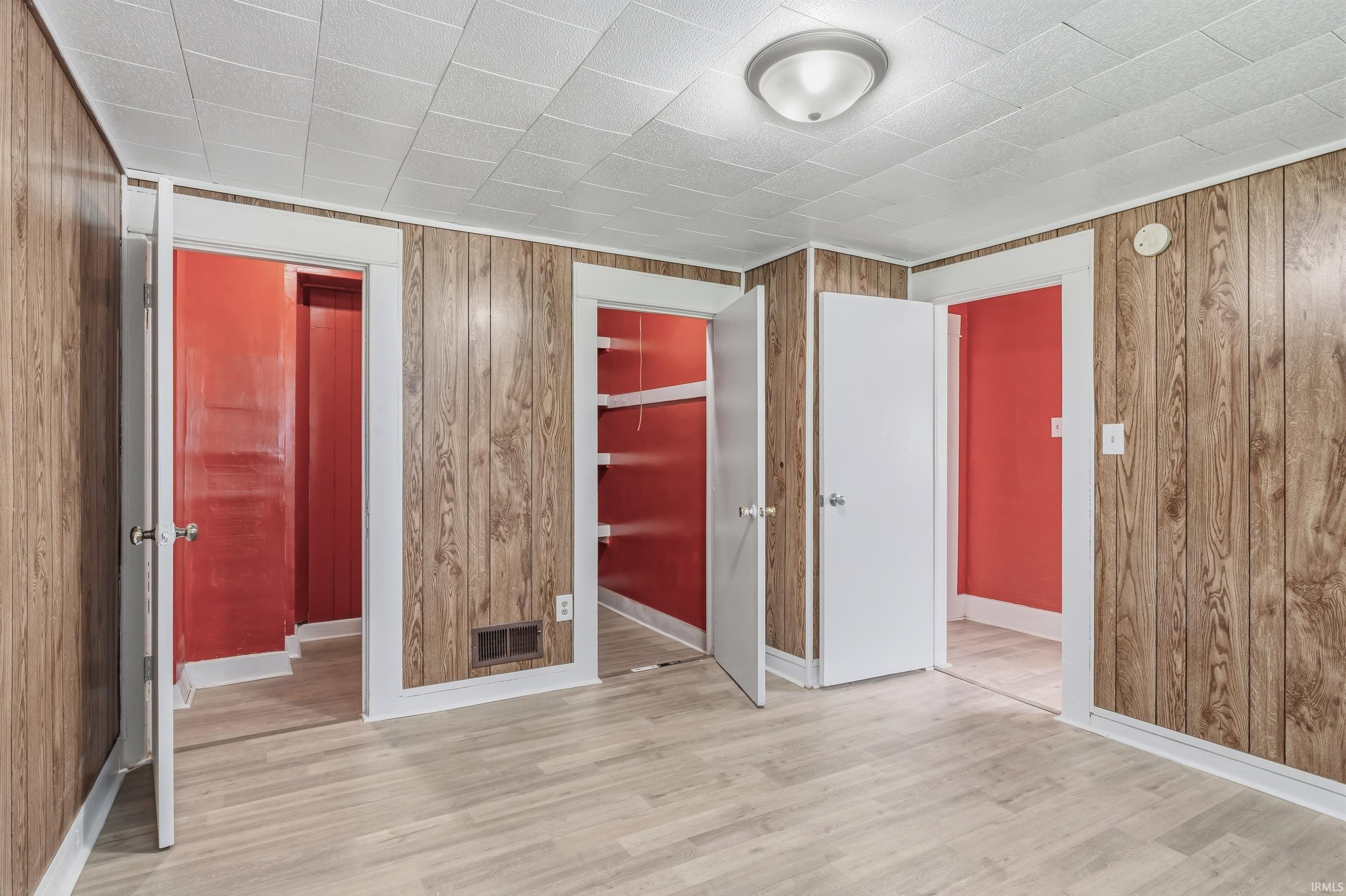 Room featuring wood-finish paneling, light wood-finish flooring, and white trim