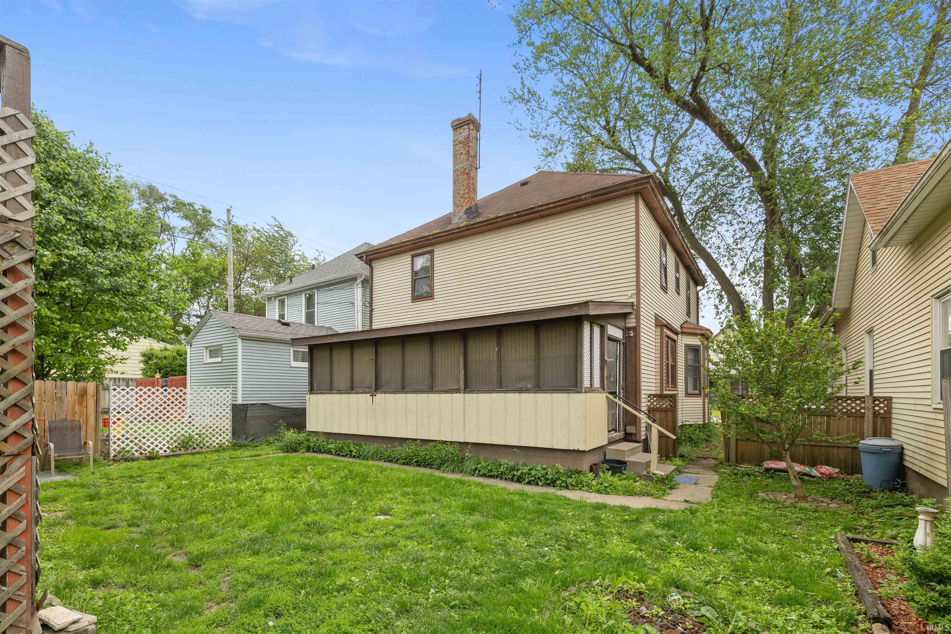 Expansive backyard featuring a manicured lawn, established trees, and a screened-in porch with direct exterior access