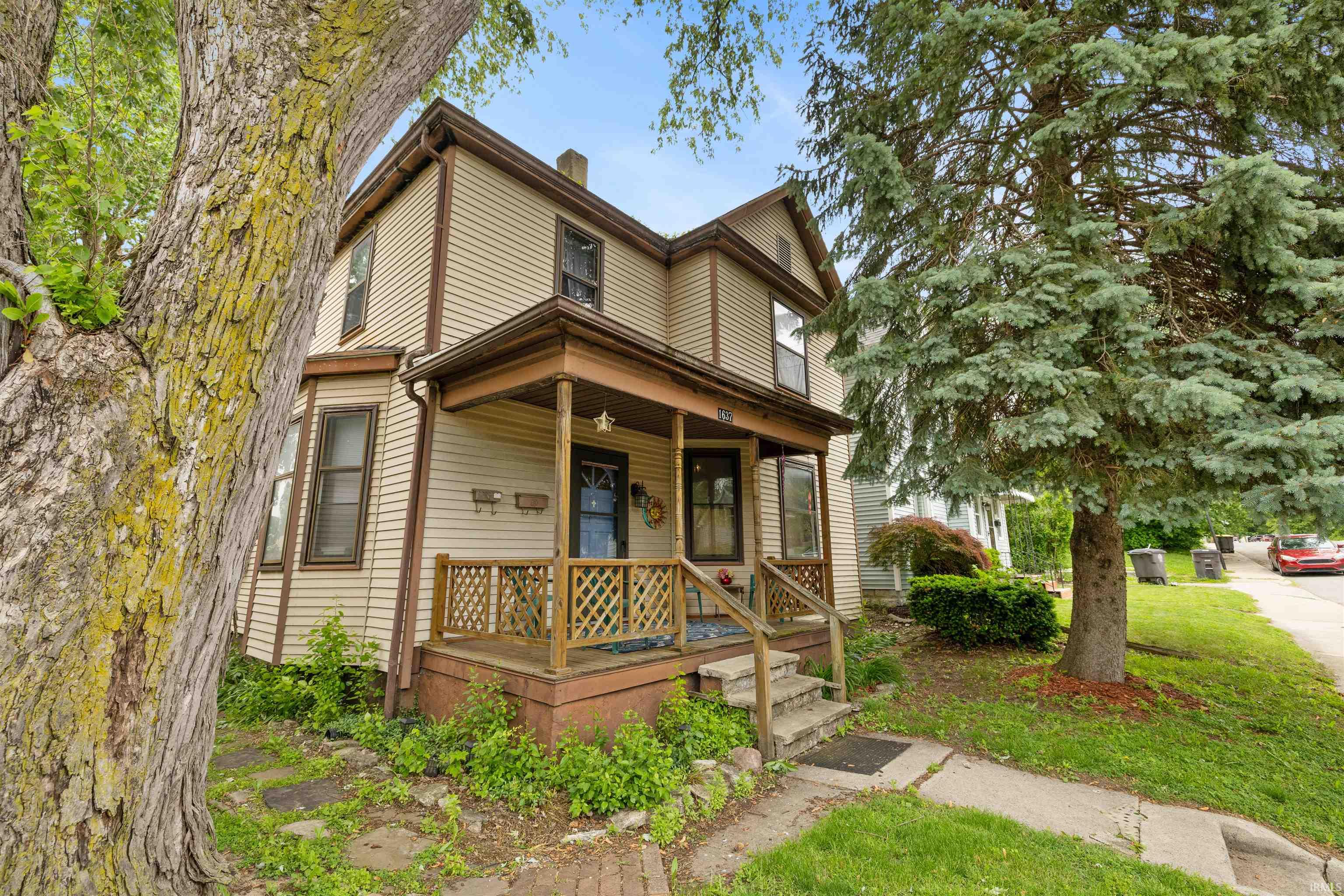Two-story exterior with horizontal siding, covered front porch, bay window, and gabled roofline