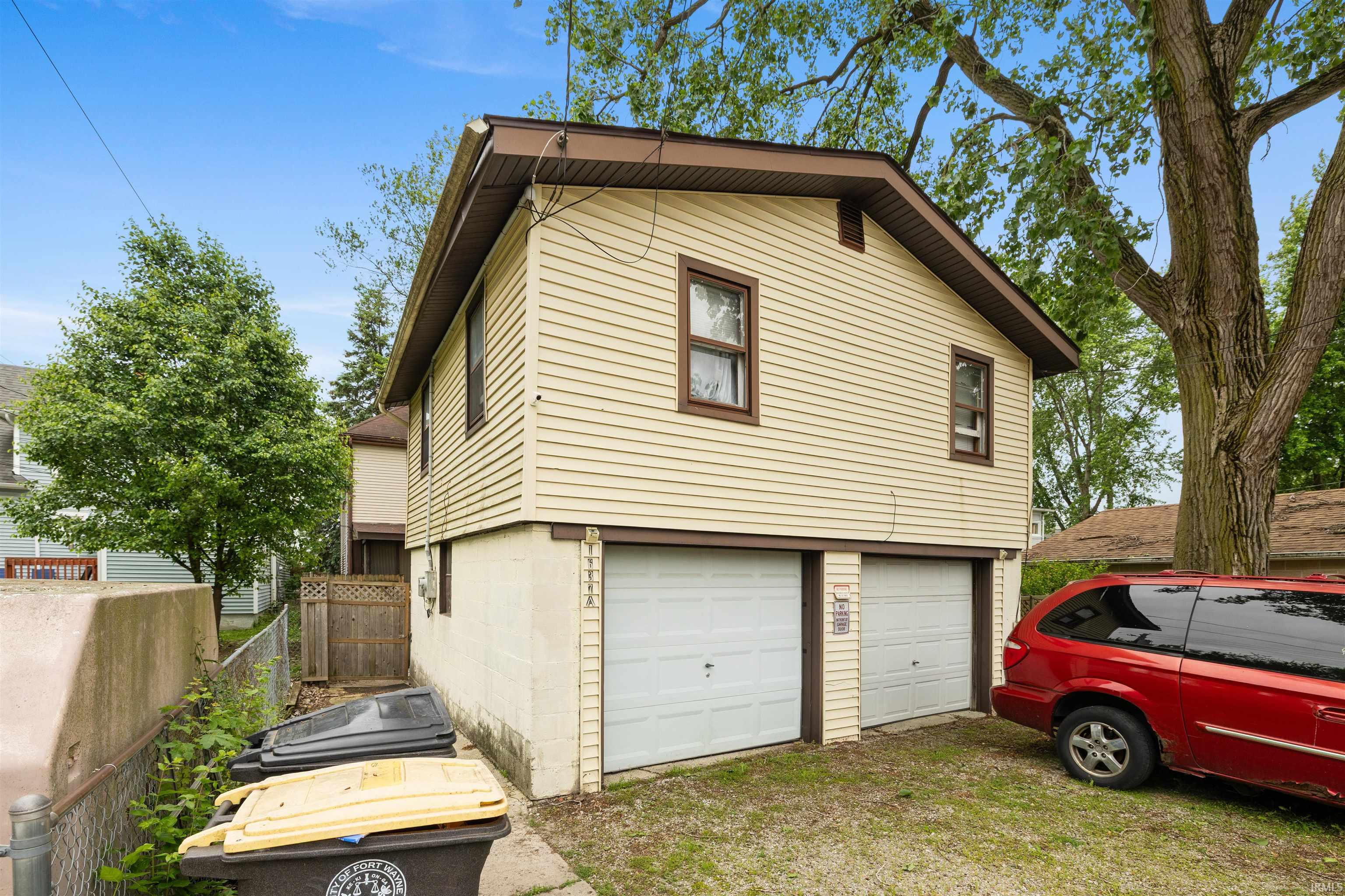 Two-story structure with light-colored siding, a brown trim, and a two-car garage