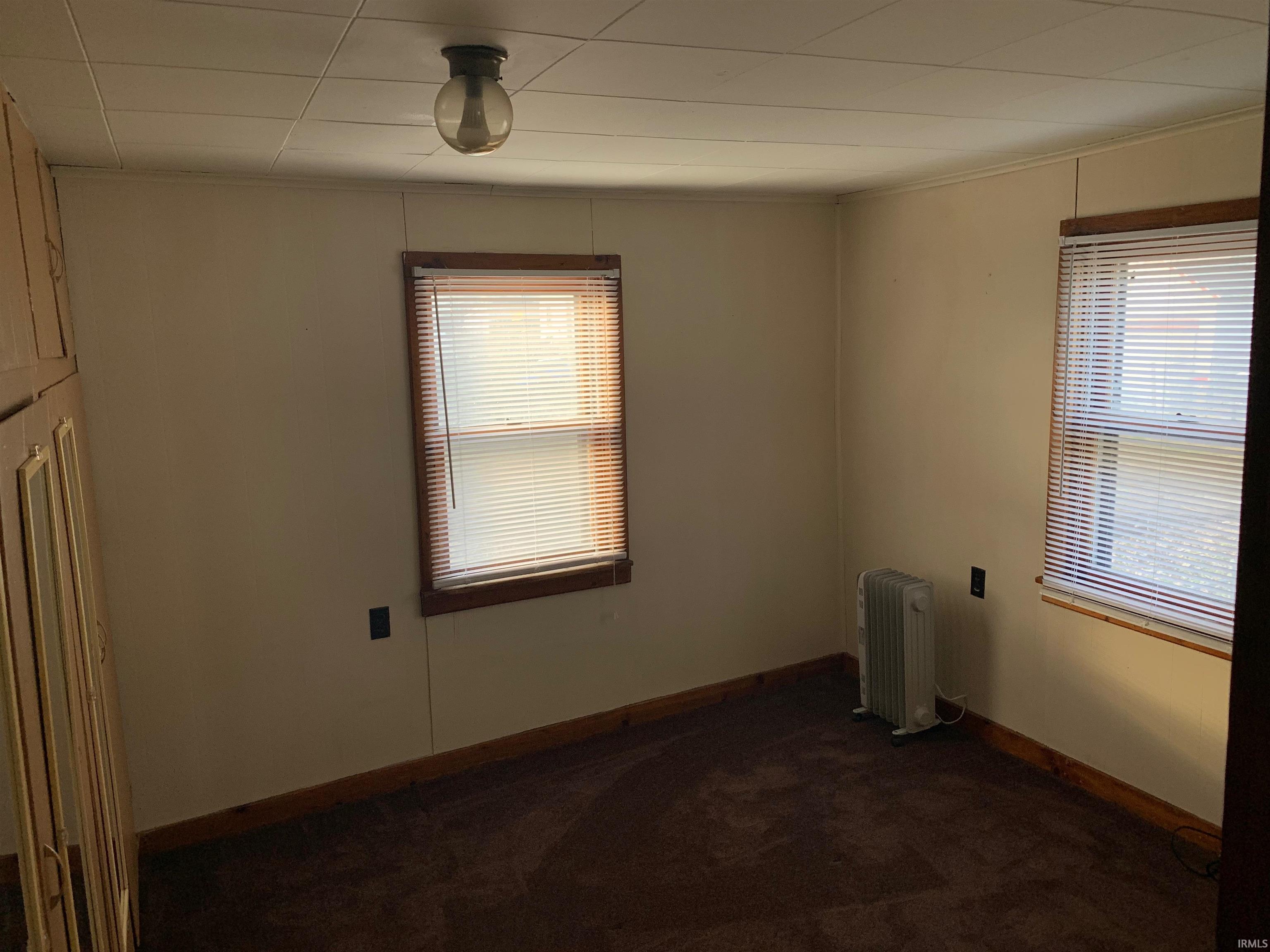 Room featuring two windows with wood trim, wall-to-wall carpeting, and a built-in cabinetry unit