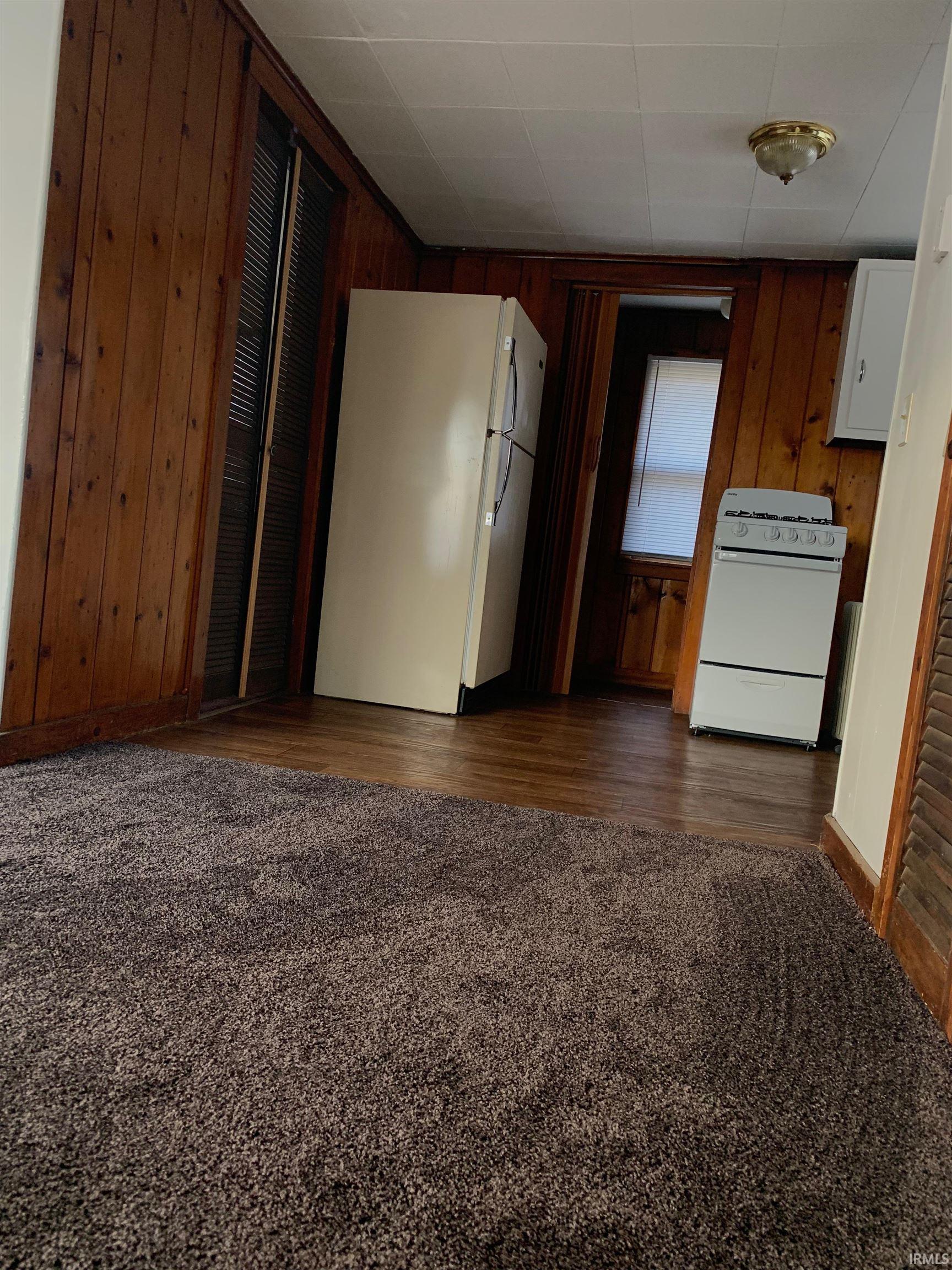 Warm wood-paneling accents the room, complemented by wood-finish flooring