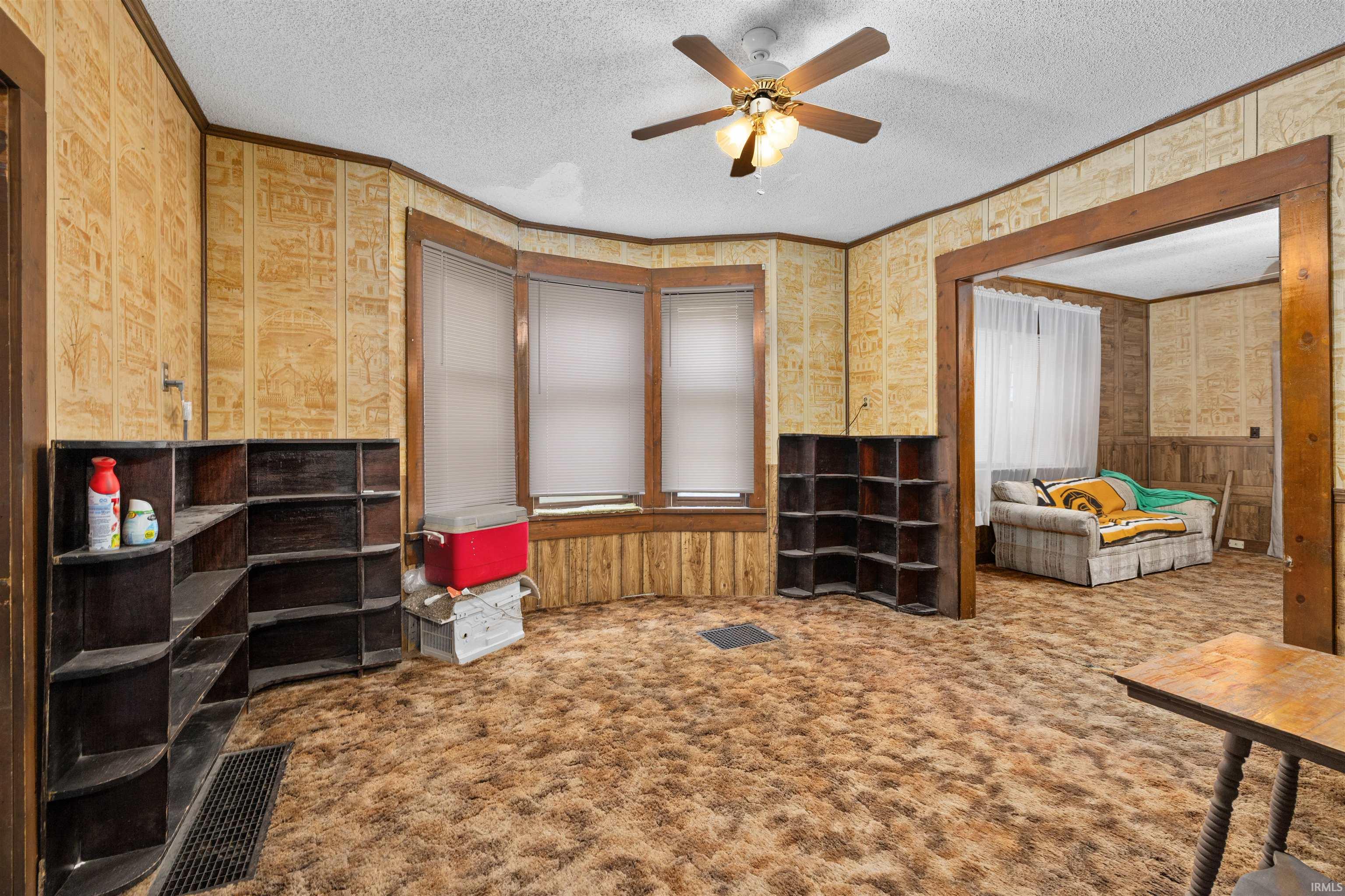 Room featuring textured wallpaper, wood paneling, and a bay window