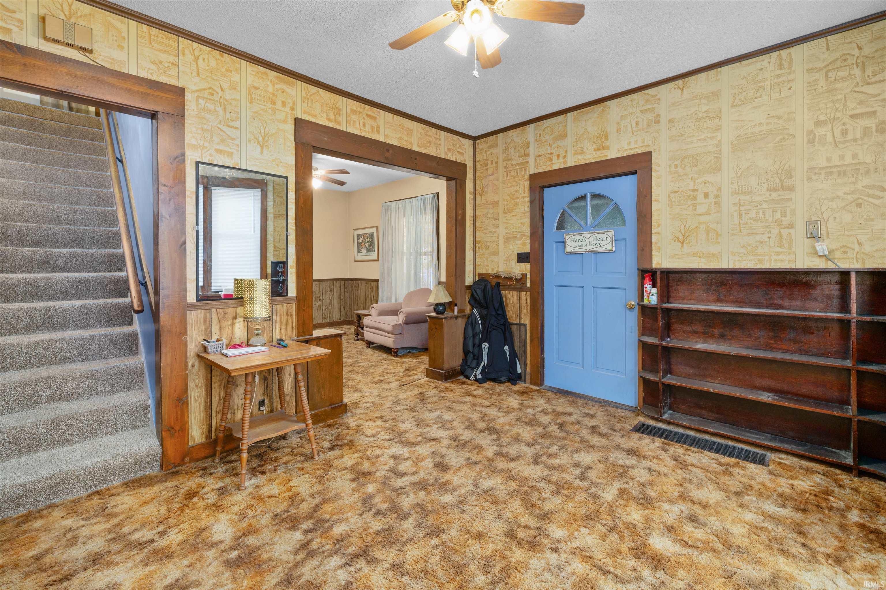 Entryway featuring a light blue door with a decorative window, a built-in wooden bookshelf, and a ceiling fan