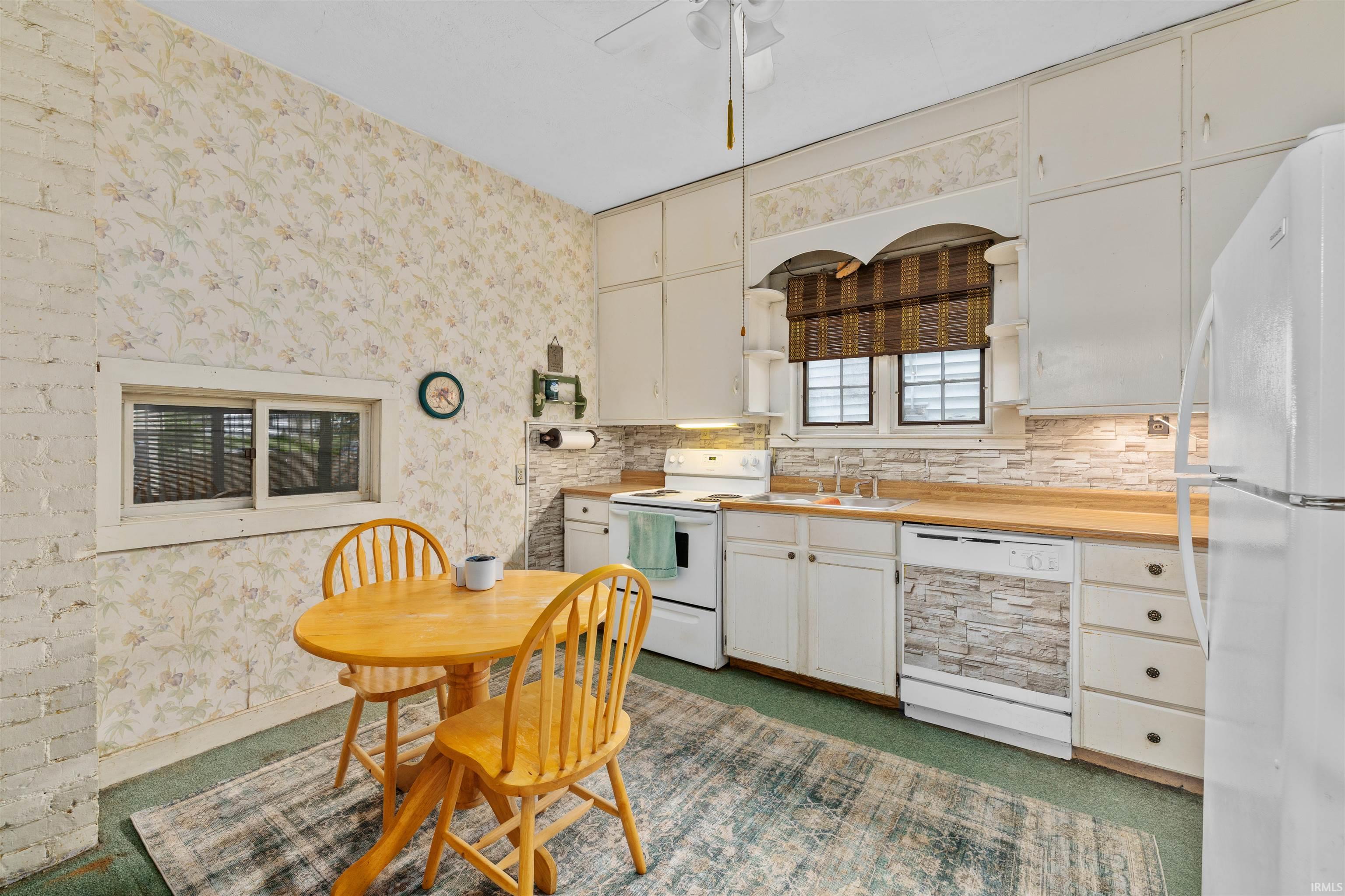 Kitchen featuring white cabinetry, light wood-finish countertops, and a stacked stone-look backsplash