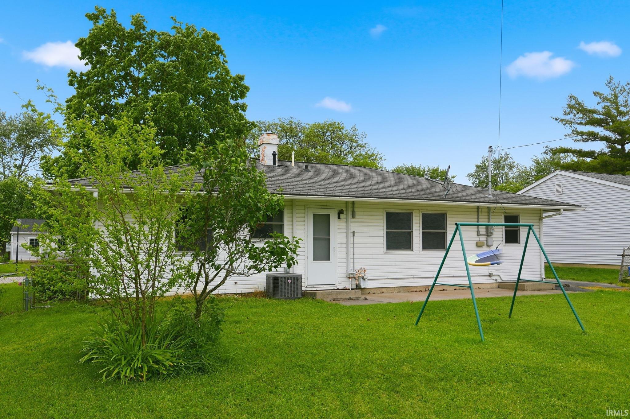 Expansive green lawn with mature trees and a rear concrete patio