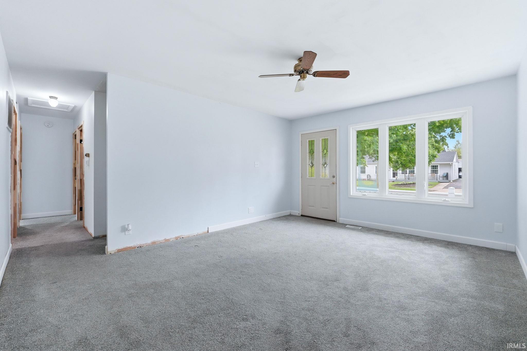 Spacious living area featuring light blue walls and neutral gray carpet
