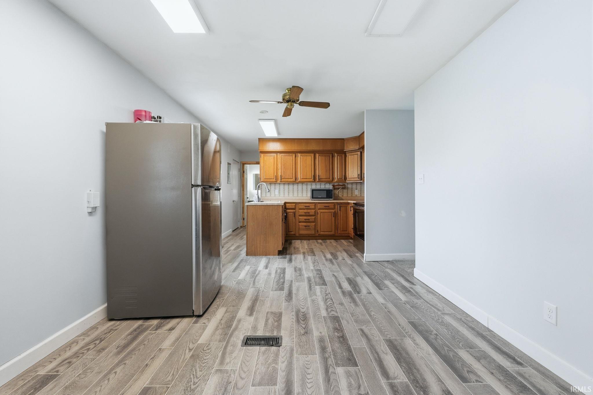 Kitchen area featuring wood-finish flooring, light cabinetry, and a ceiling fan