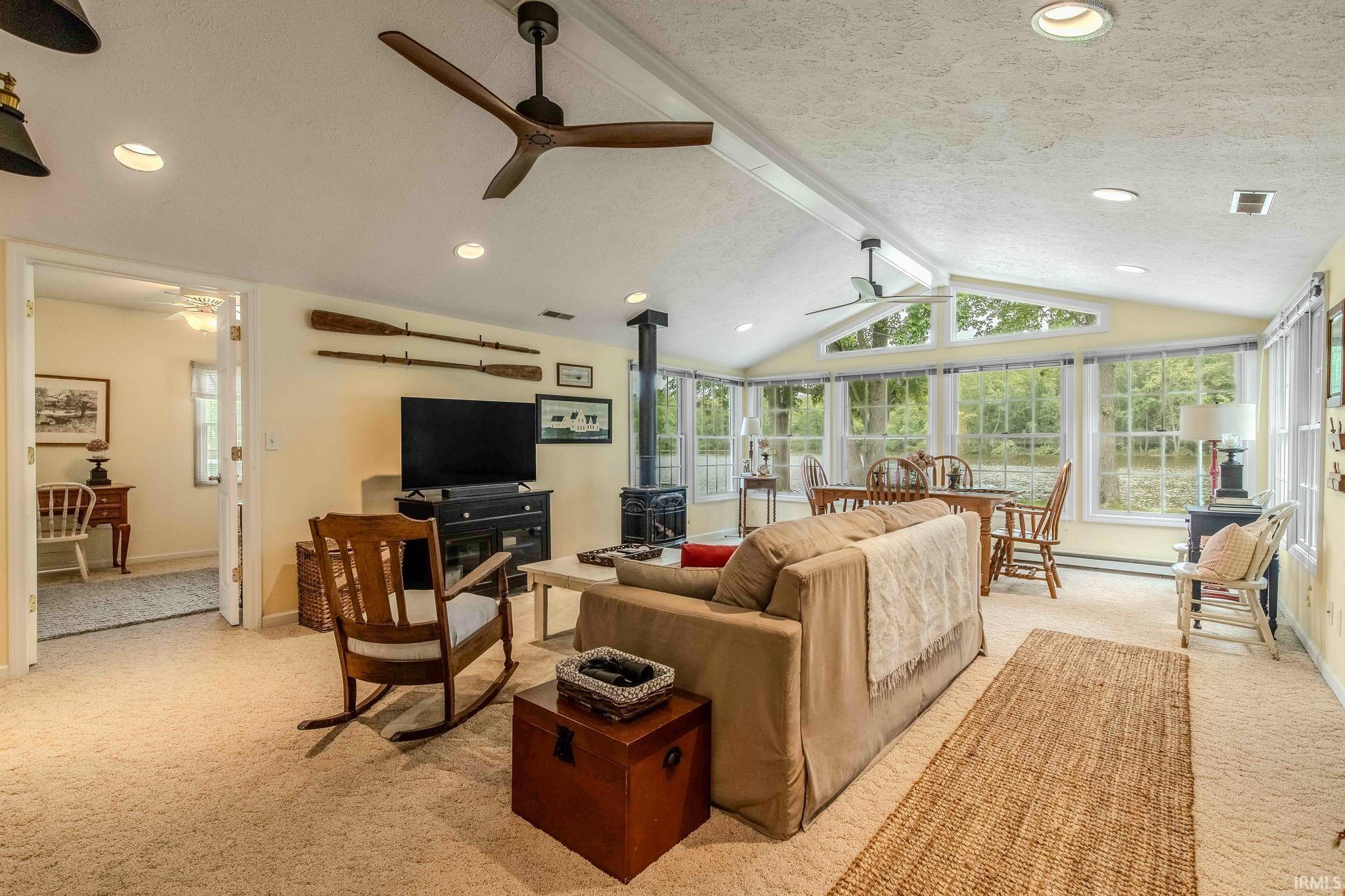 Spacious living area featuring expansive windows, a vaulted ceiling, recessed lighting, and a gas stove