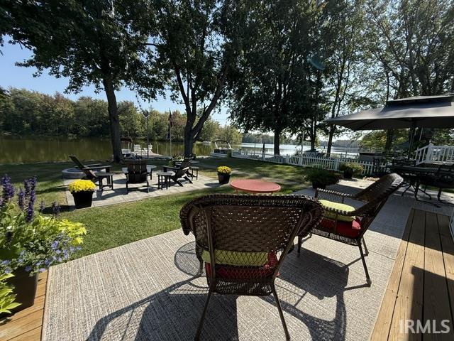 Expansive rear yard featuring a manicured lawn, established trees, and a visible body of water