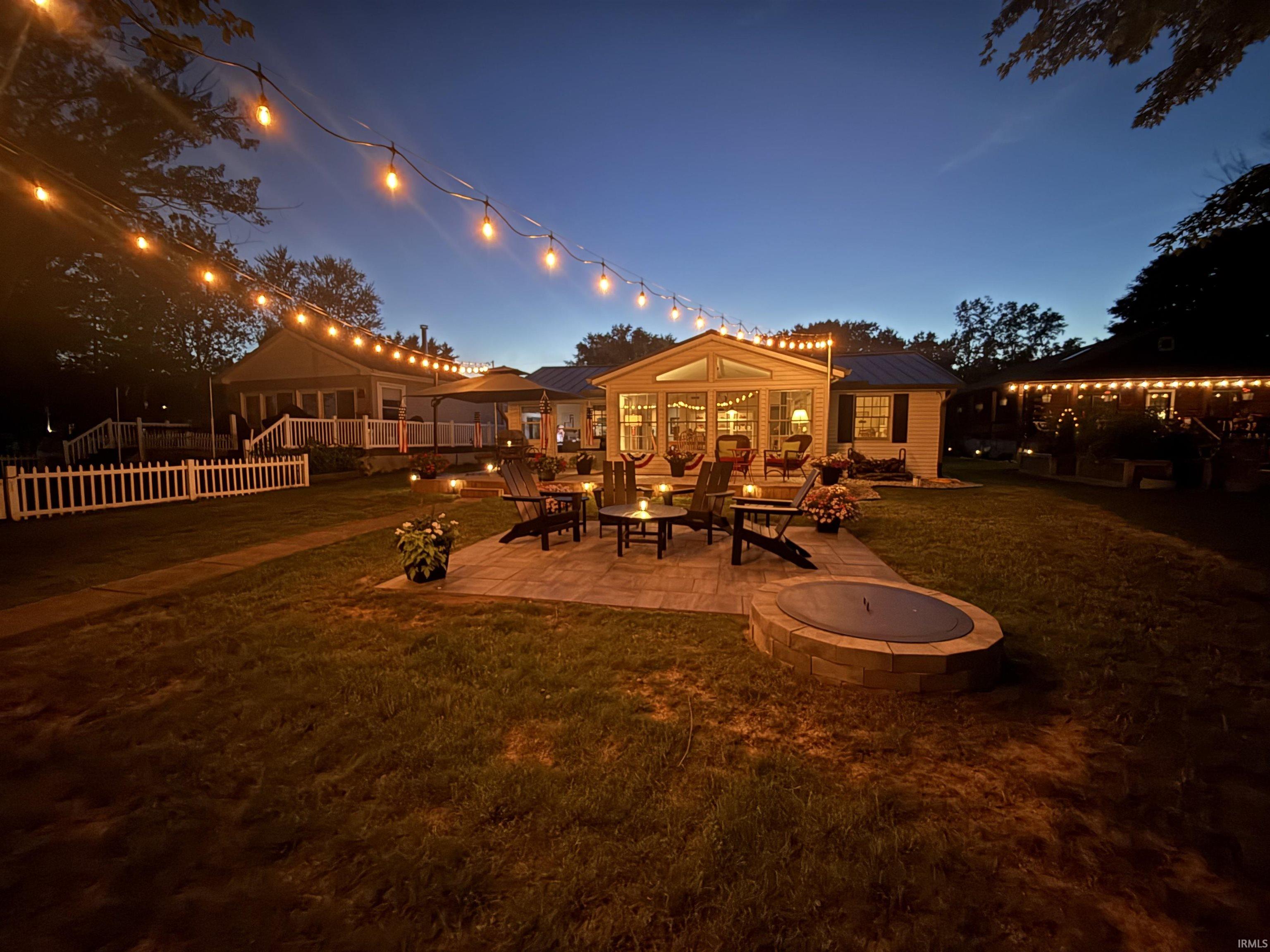 Expansive backyard featuring a paver patio with a built-in fire pit.