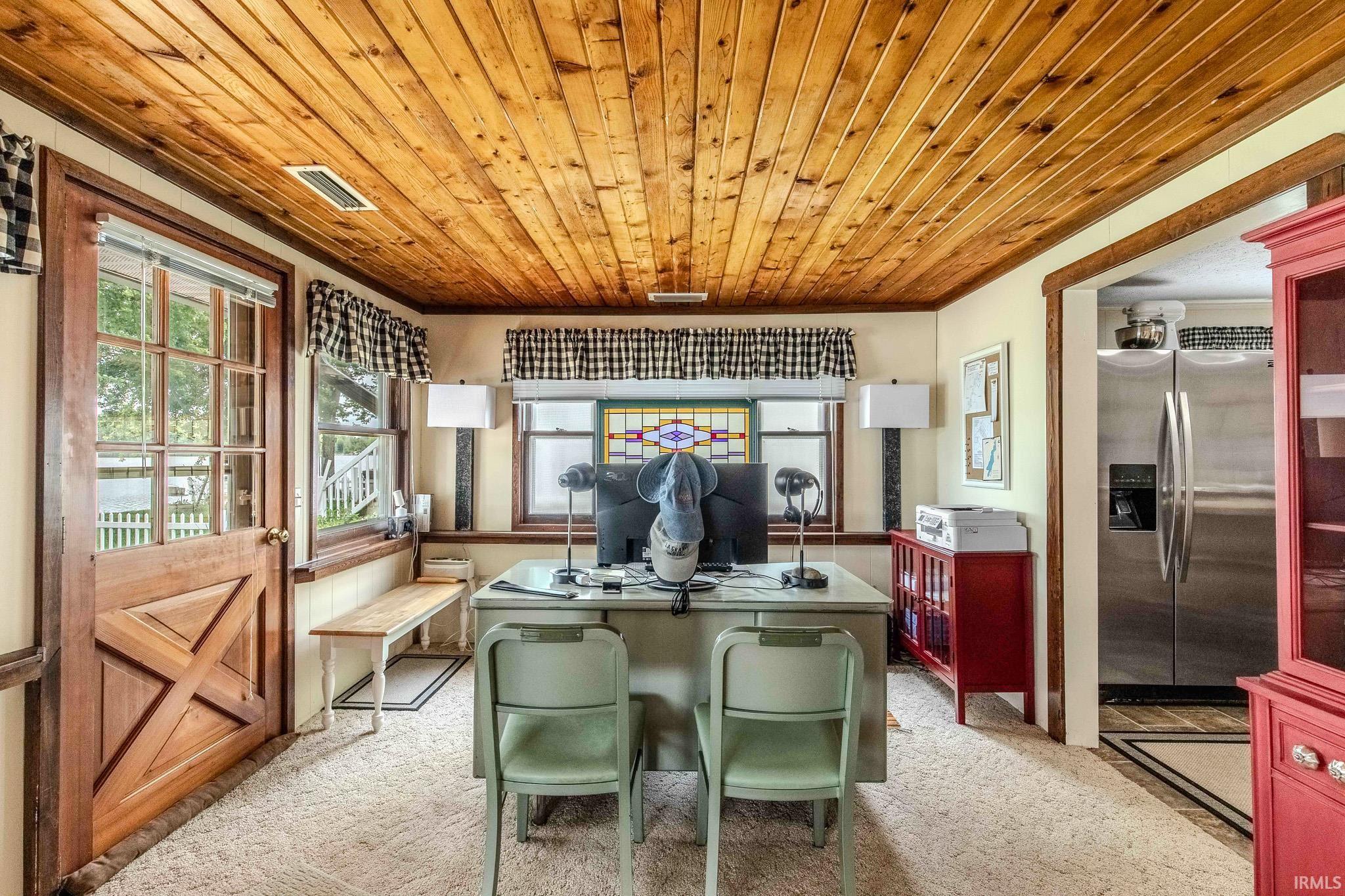 Room featuring a wood-panel ceiling, multiple windows, and a Dutch door with clear glass panes