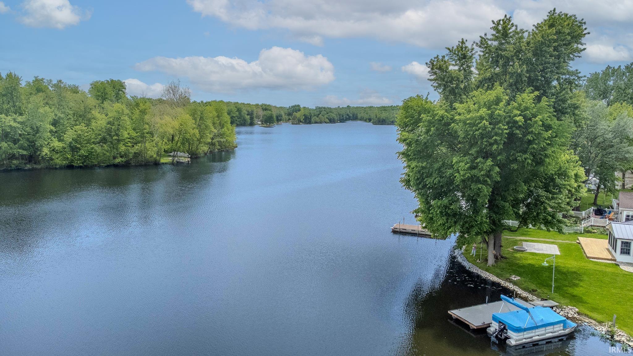 Expansive waterfront property featuring a large body of water, lush green trees, and two private docks