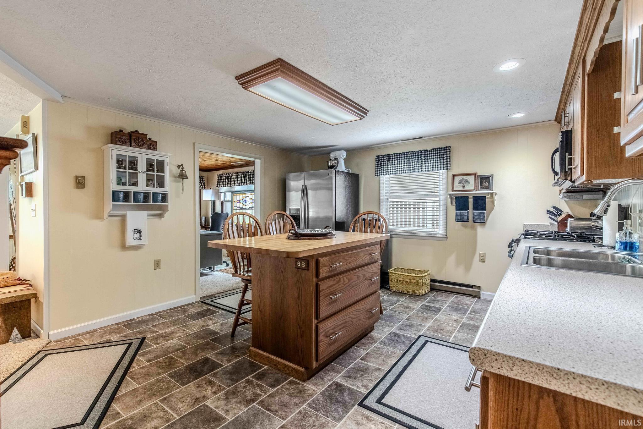Kitchen featuring a central wood island with seating, a stainless steel refrigerator, and a gas range