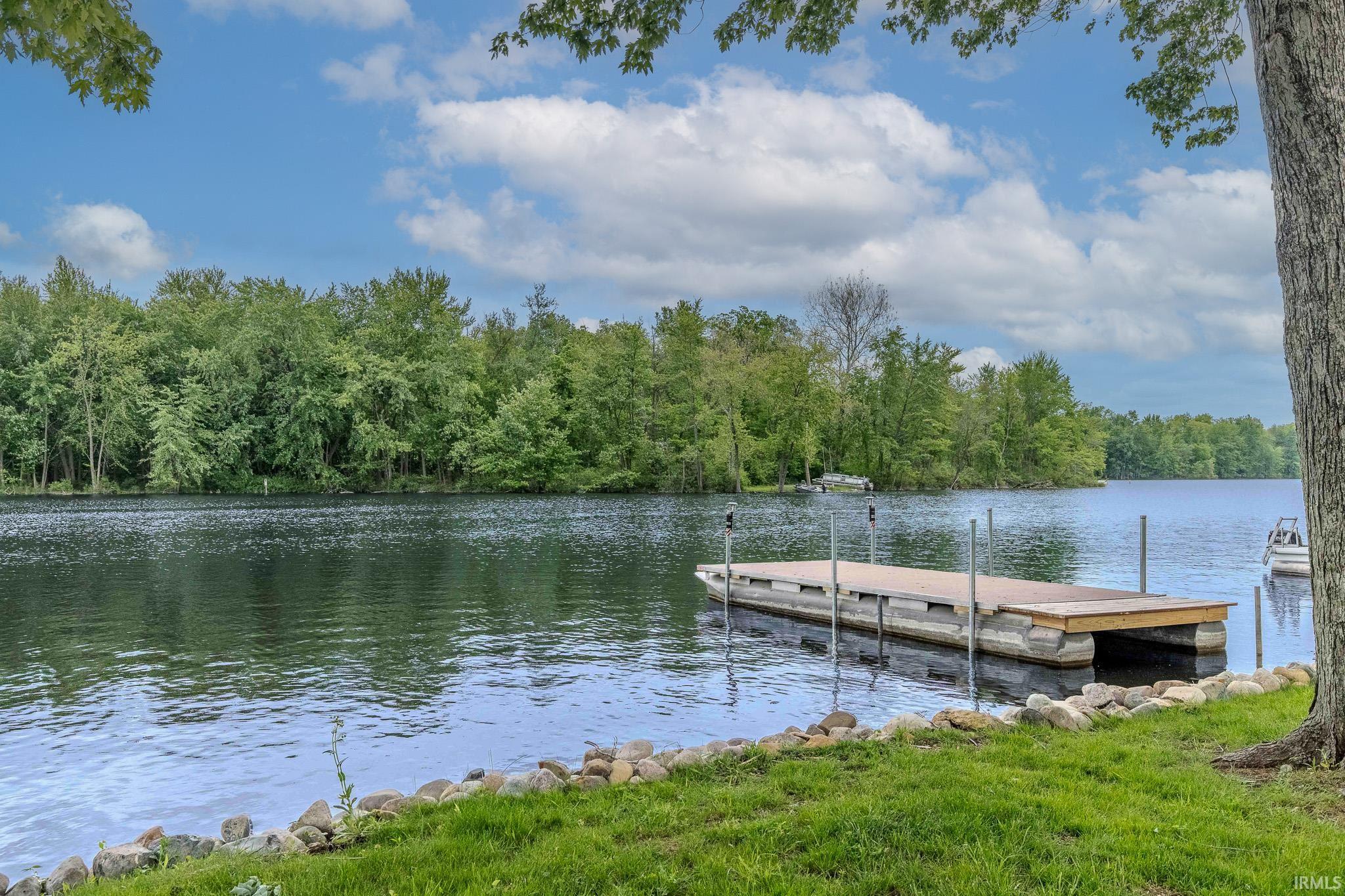Lakefront property featuring a private dock, natural rock retaining wall, and expansive shoreline with mature trees