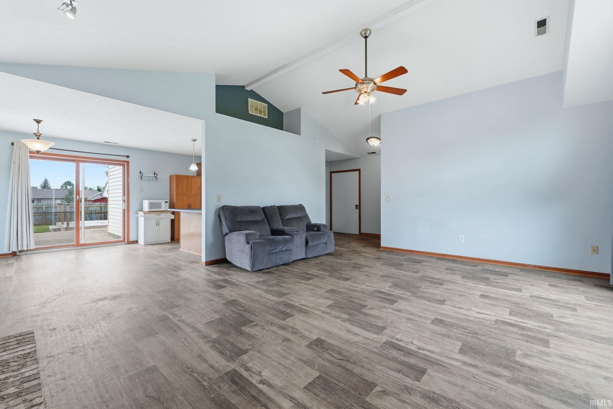 Spacious interior featuring wood-finish flooring, vaulted ceilings, and a ceiling fan with integrated lighting
