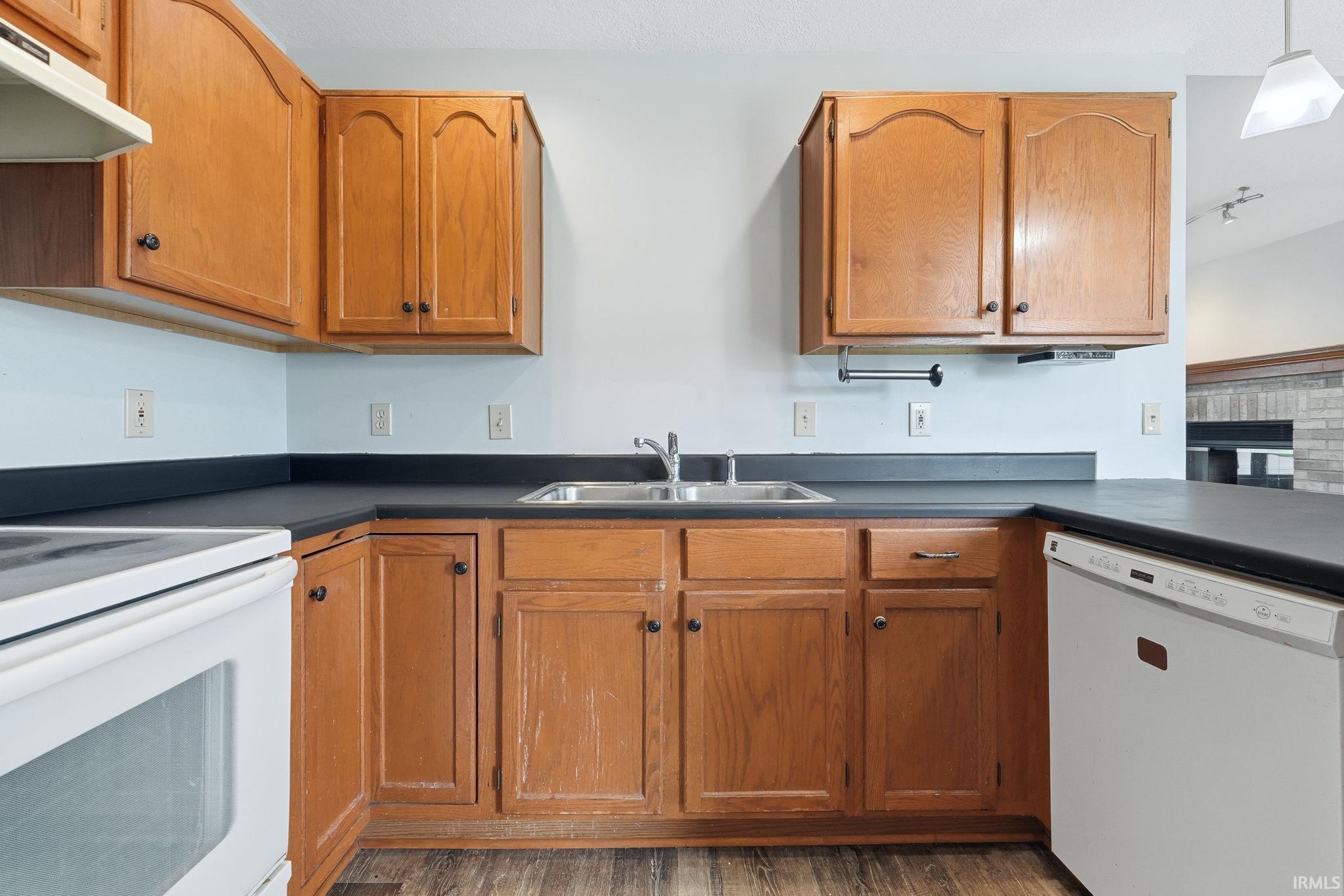 Kitchen featuring wood-finish cabinetry, dark countertops, and a double basin stainless steel sink
