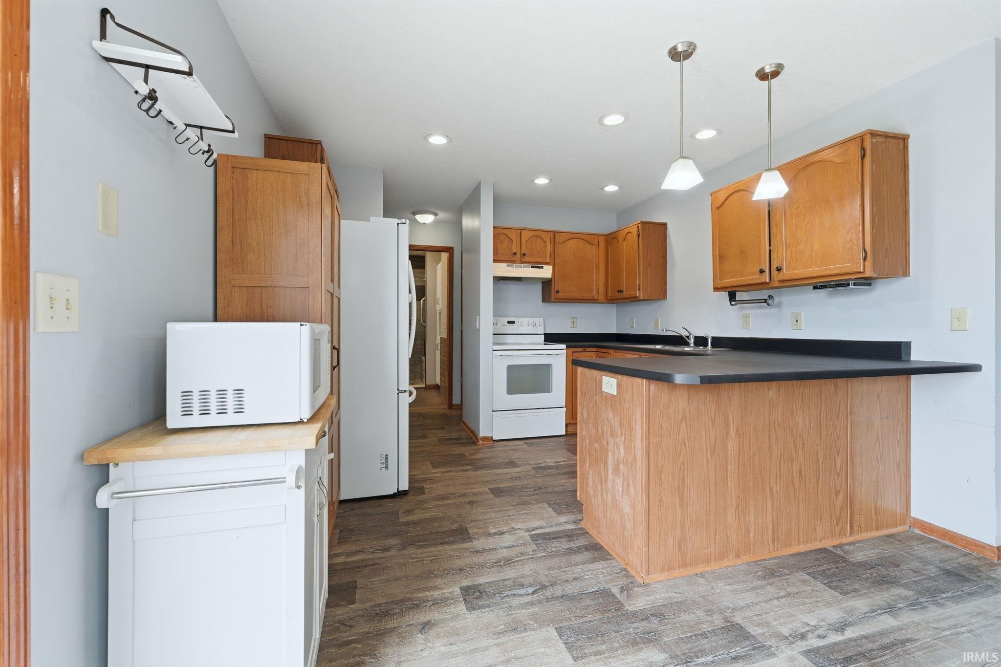 Kitchen featuring wood-finish cabinetry, dark countertops, and wood-finish flooring