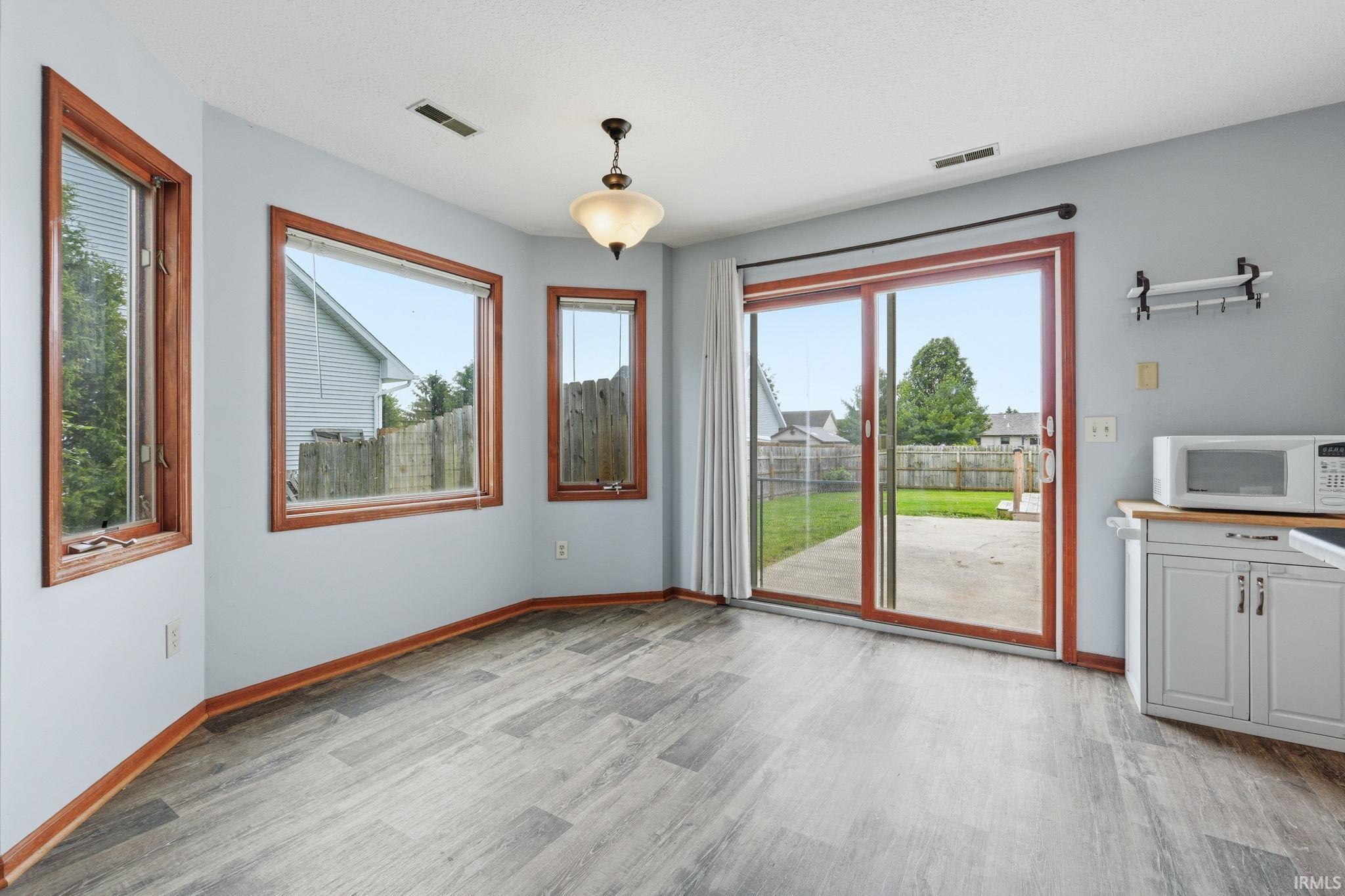 Spacious room featuring wood-finish flooring, light grey wall paint, and multiple windows with wood trim