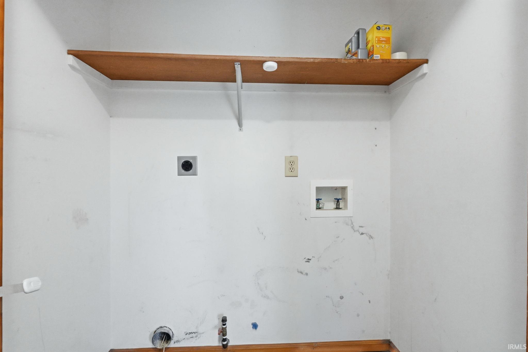 Dedicated utility area with wood-finish shelving, power outlets, and water hookups
