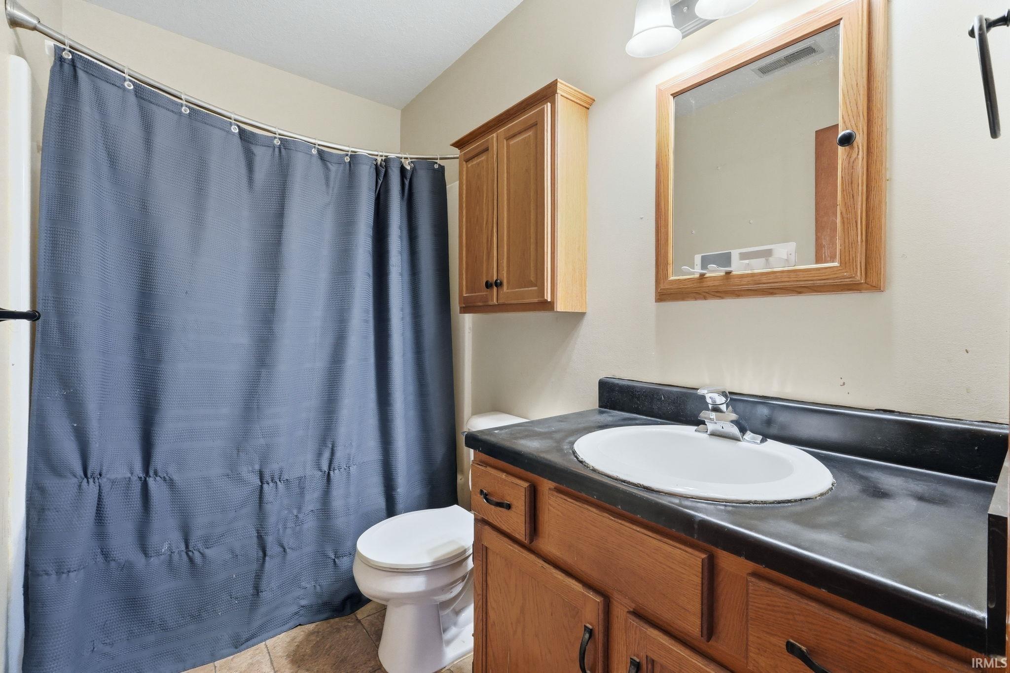Bathroom featuring a light wood-finish vanity with a dark countertop and integrated white sink
