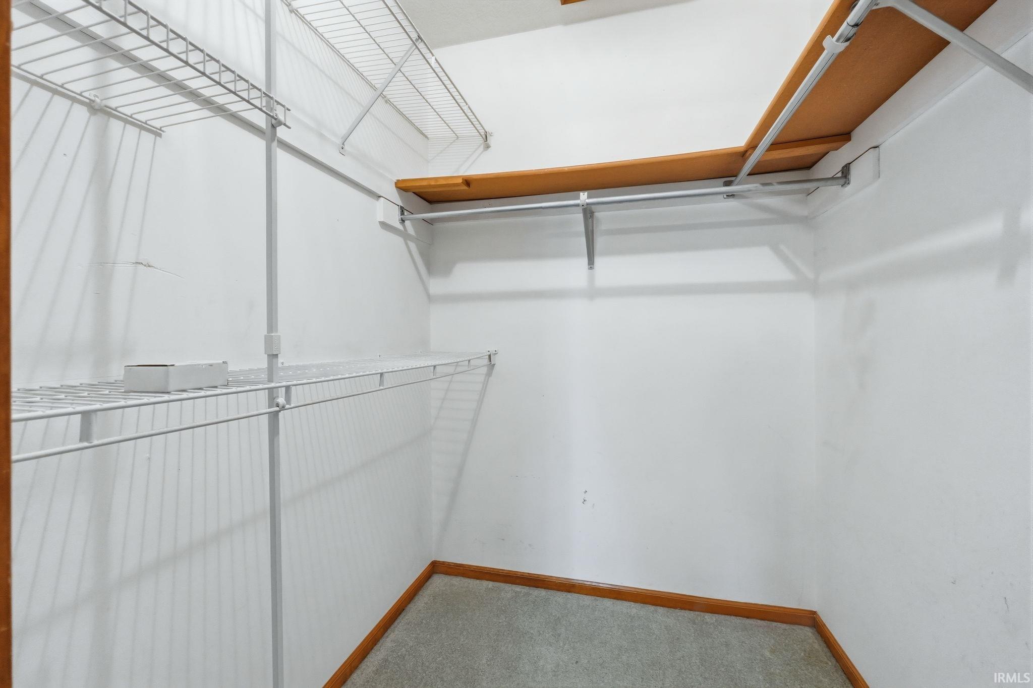 Walk-in closet featuring wire shelving, wood-finish shelving, and hanging rods