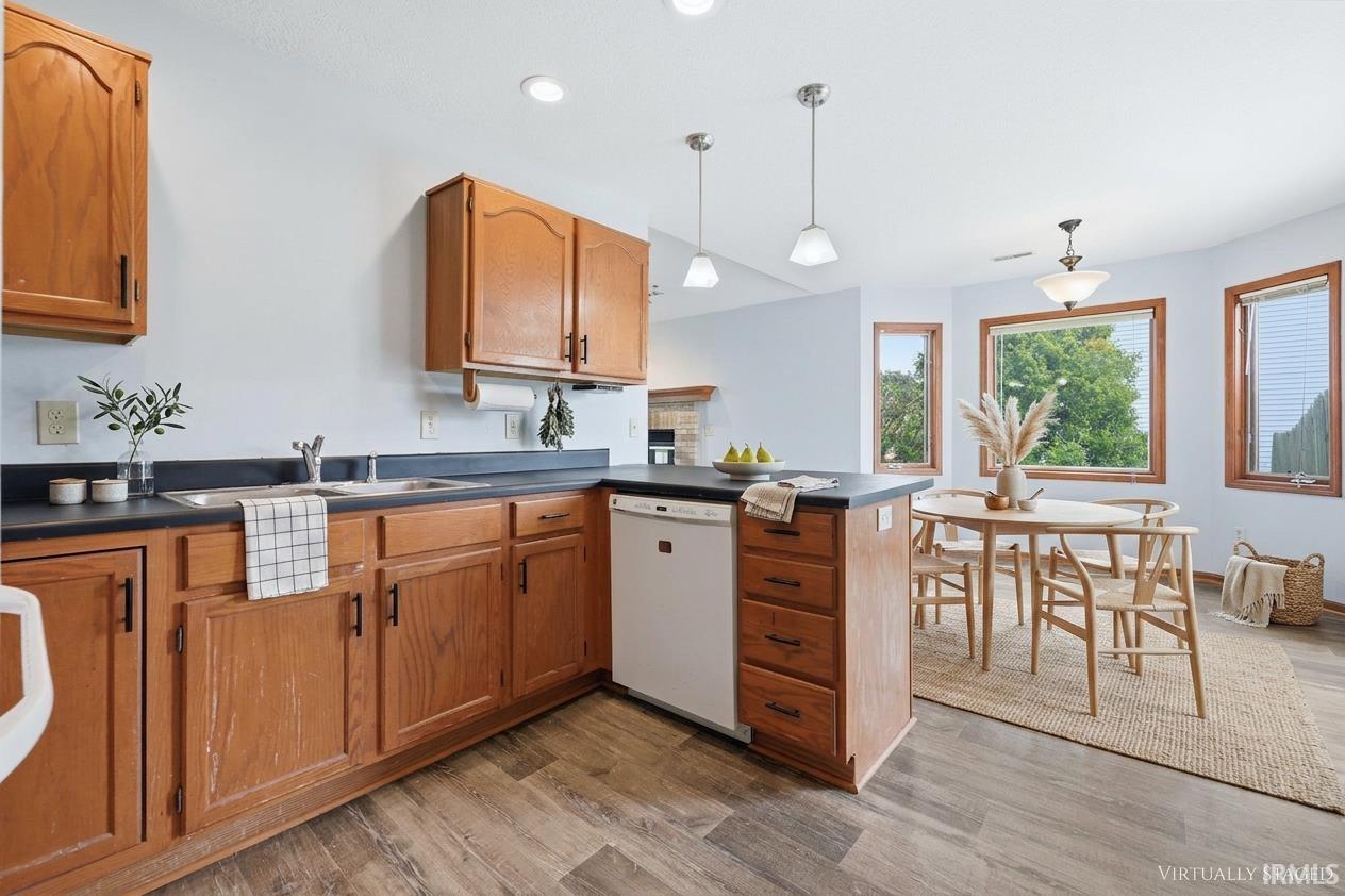 Kitchen and dining area featuring wood-finish flooring, light wood cabinetry, and dark countertops