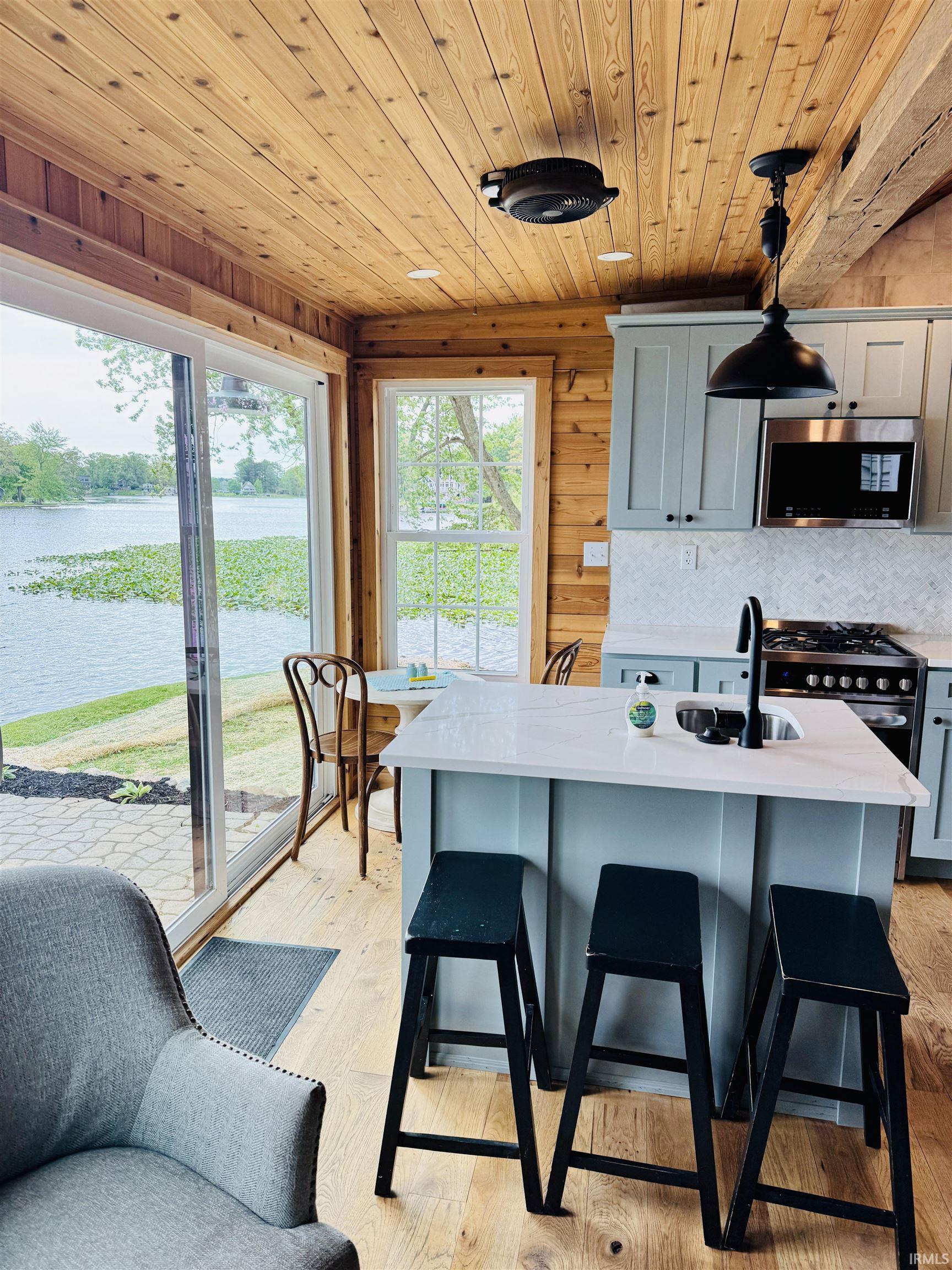 Open-concept kitchen featuring light wood-finish flooring and plank wood ceilings