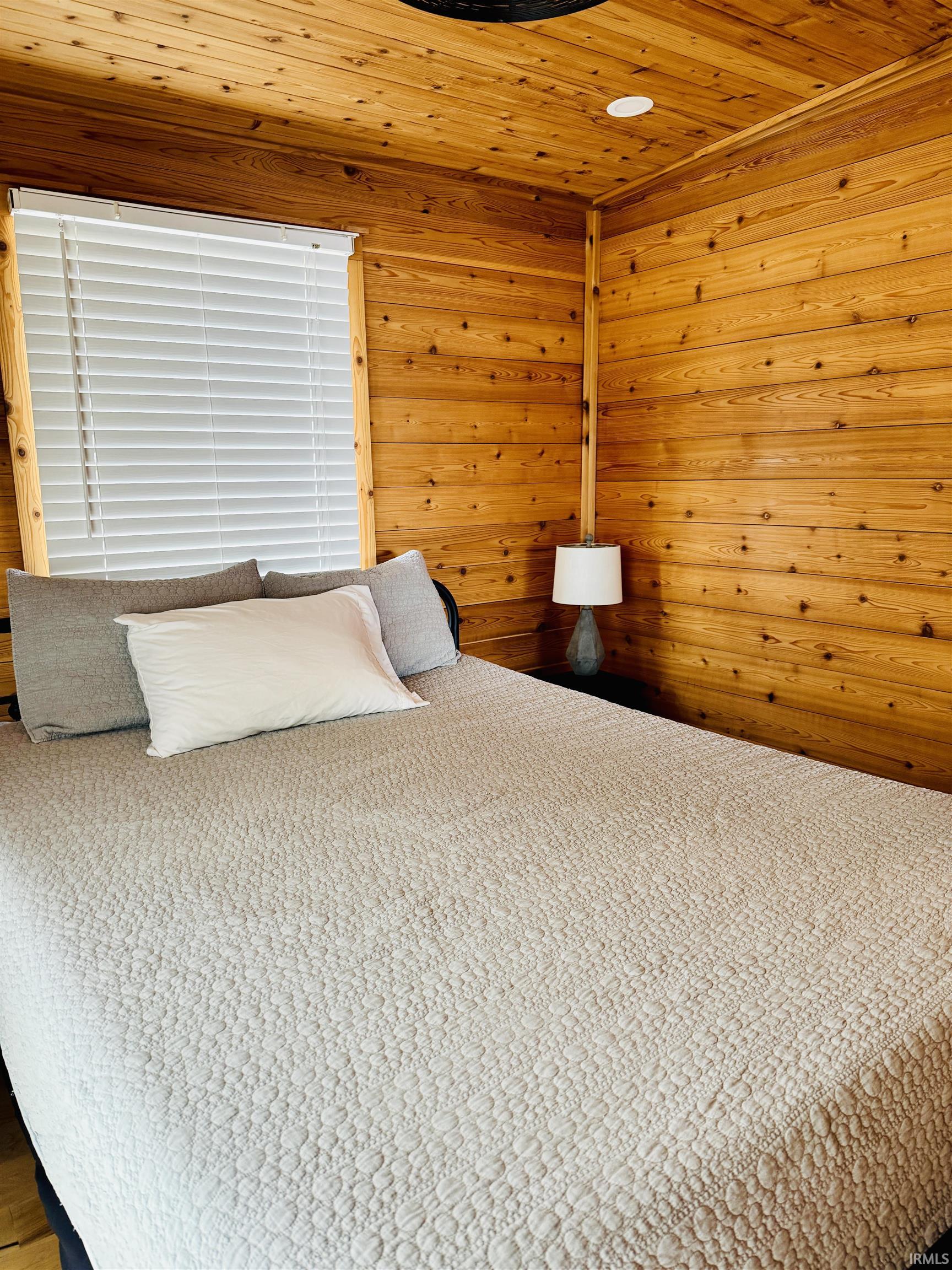 Wood-paneled room featuring a slatted wood ceiling, recessed lighting, and a window with blinds