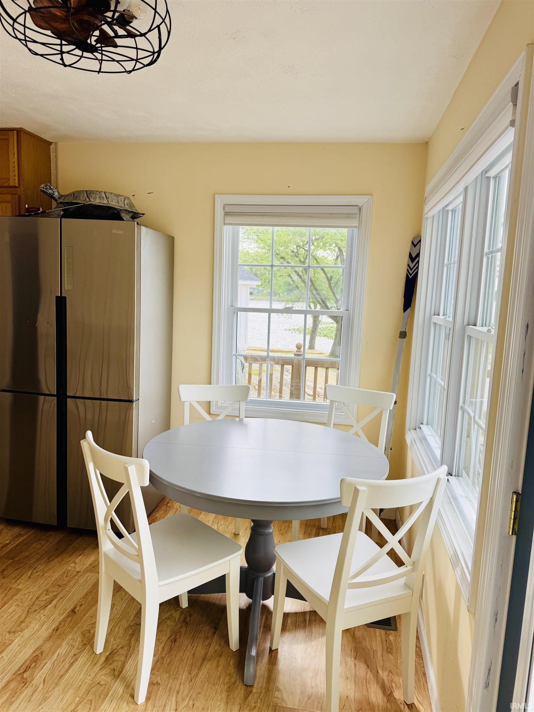 Kitchen dining area featuring wood-finish flooring, a stainless steel refrigerator, and ample natural light from multiple windows