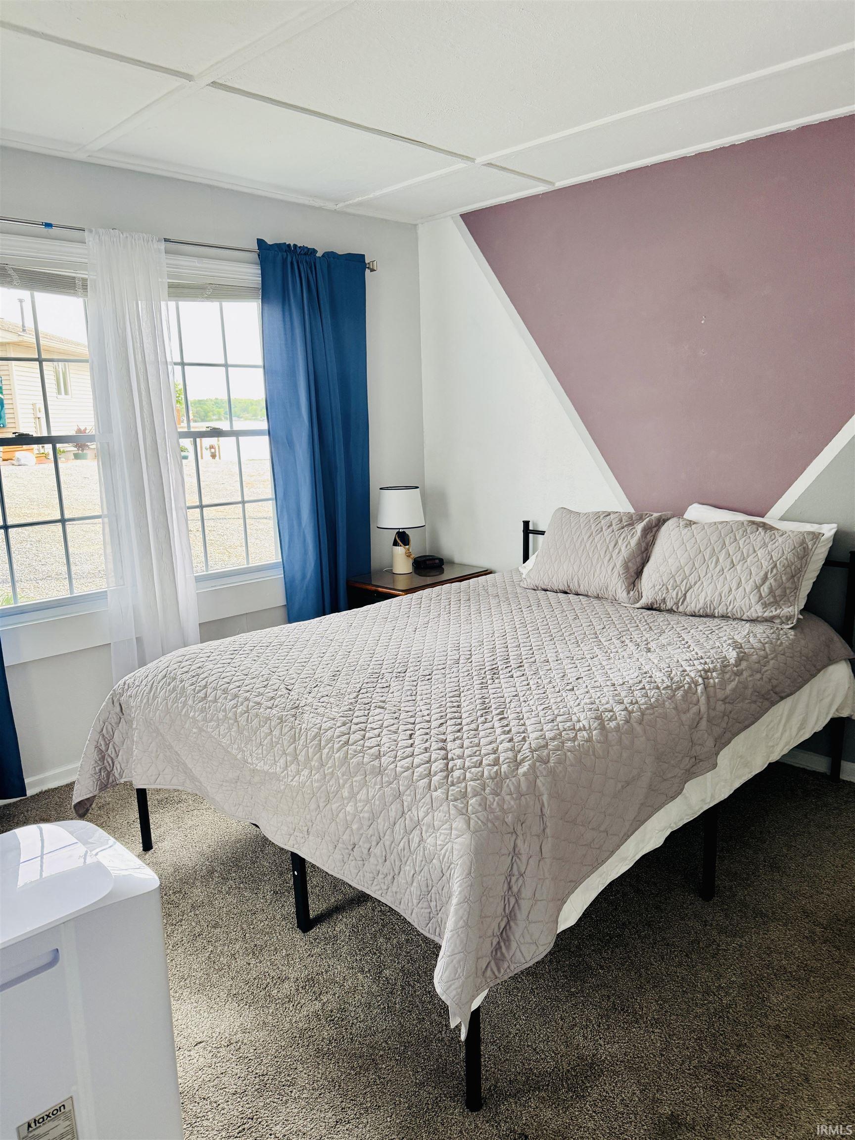 Bedroom featuring two double-hung windows, a textured ceiling, and neutral-toned carpeting