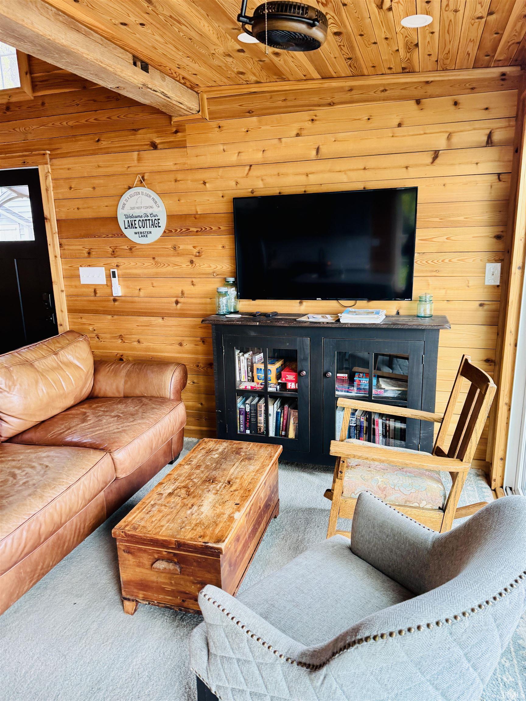 Wood-paneled interior featuring a built-in wood beam, recessed lighting, and a ceiling-mounted fan