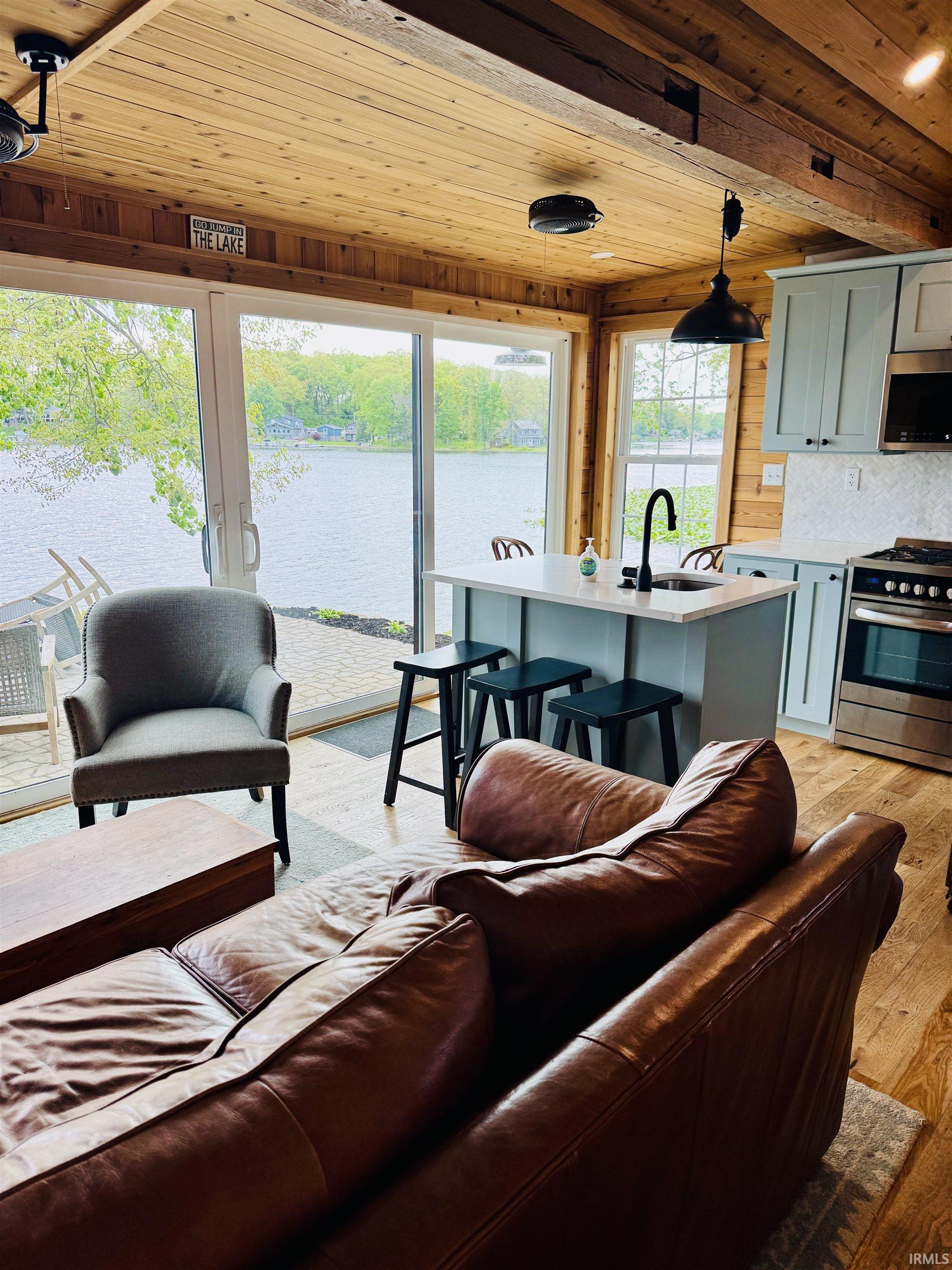 Open-concept living area featuring wood-finish flooring and a wood-paneled ceiling with exposed beams