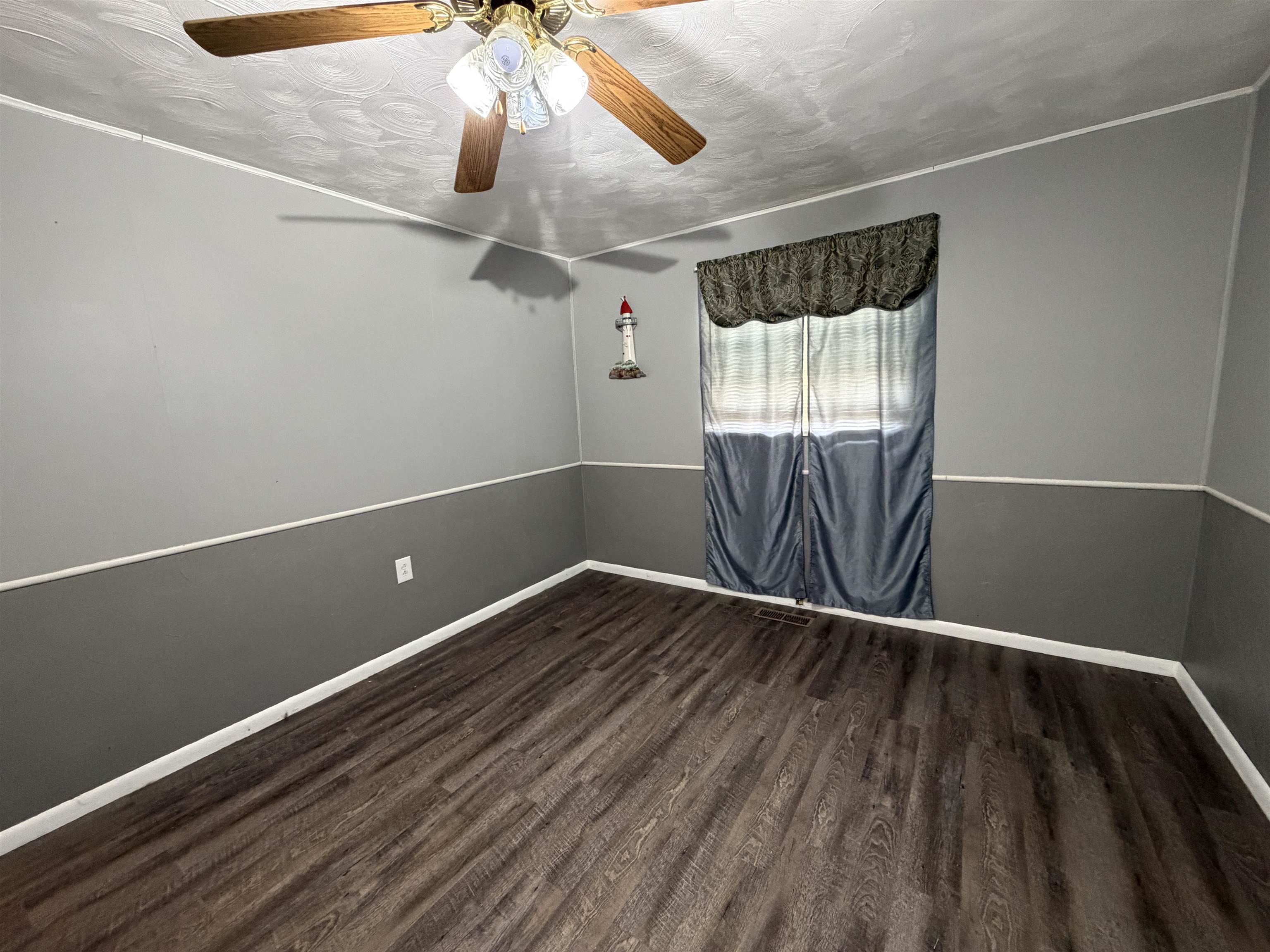Wood-finish flooring anchors this room, complemented by a two-tone gray wall treatment with white chair rail and trim