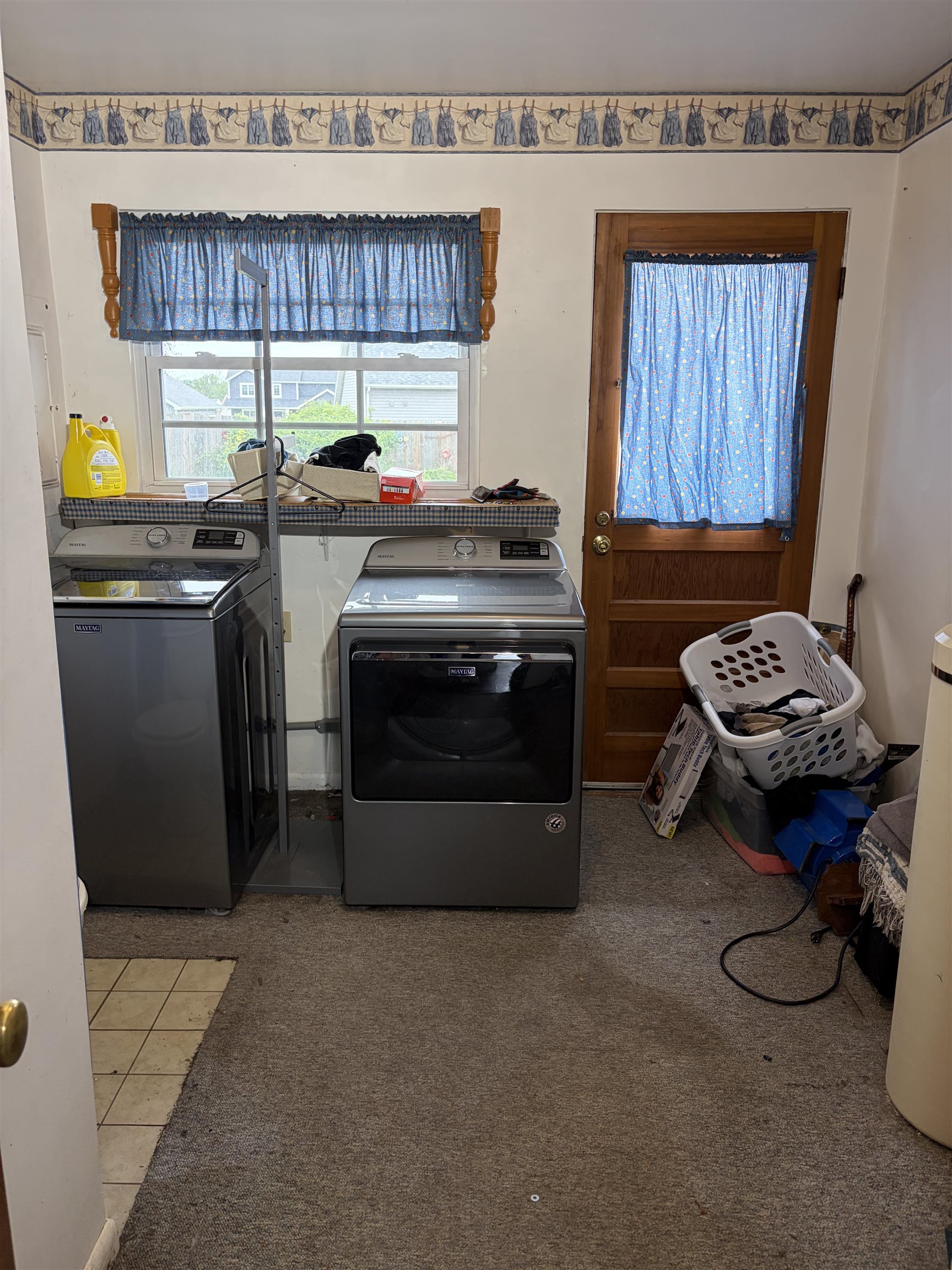 Utility area featuring a window, wood panel door, and partial carpet flooring