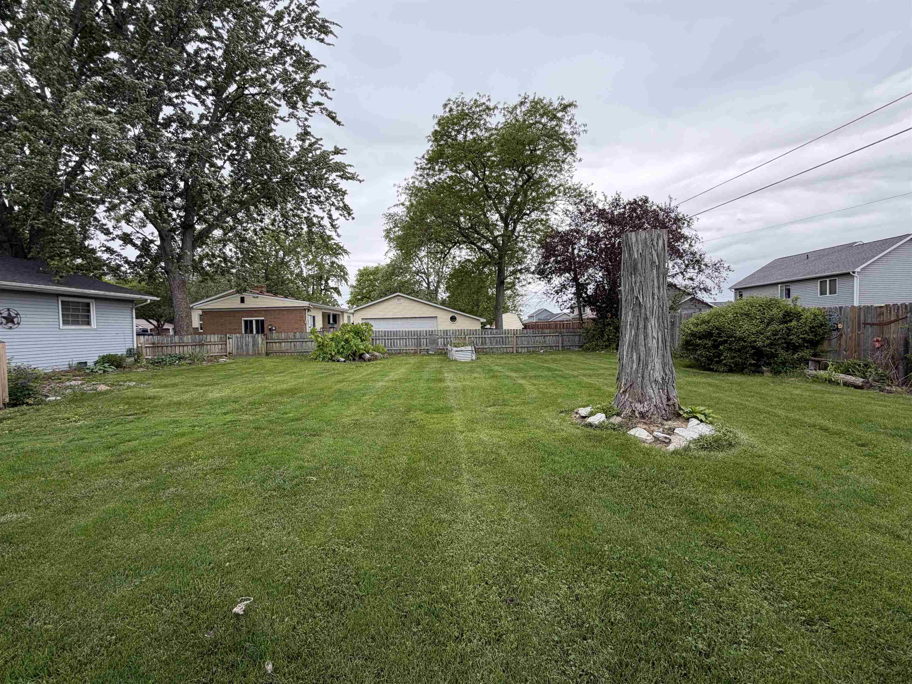 Expansive backyard featuring a lush lawn, perimeter fencing, and mature trees