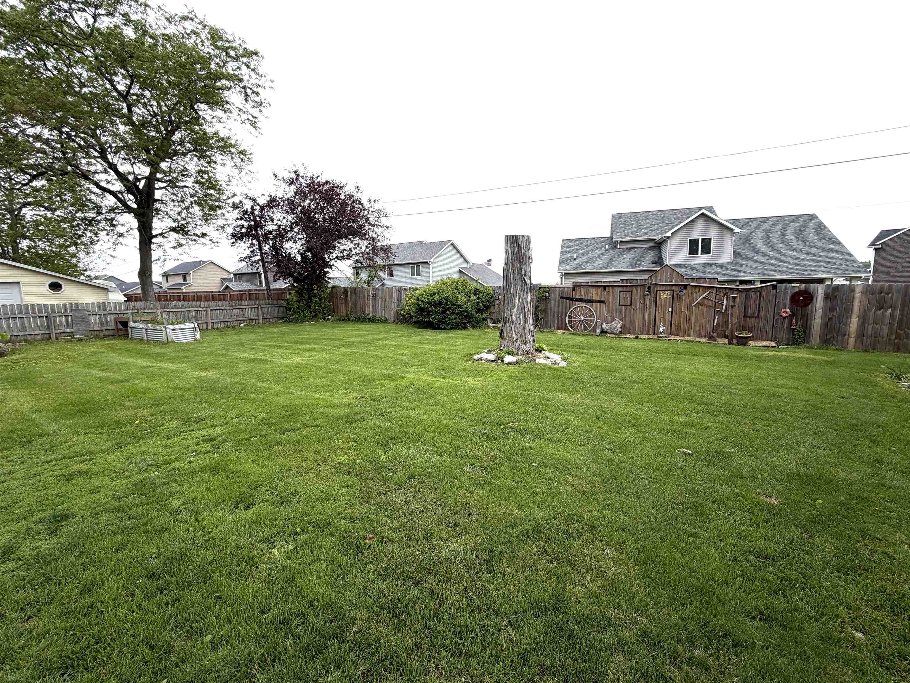 Expansive green lawn with mature trees and a perimeter wooden fence