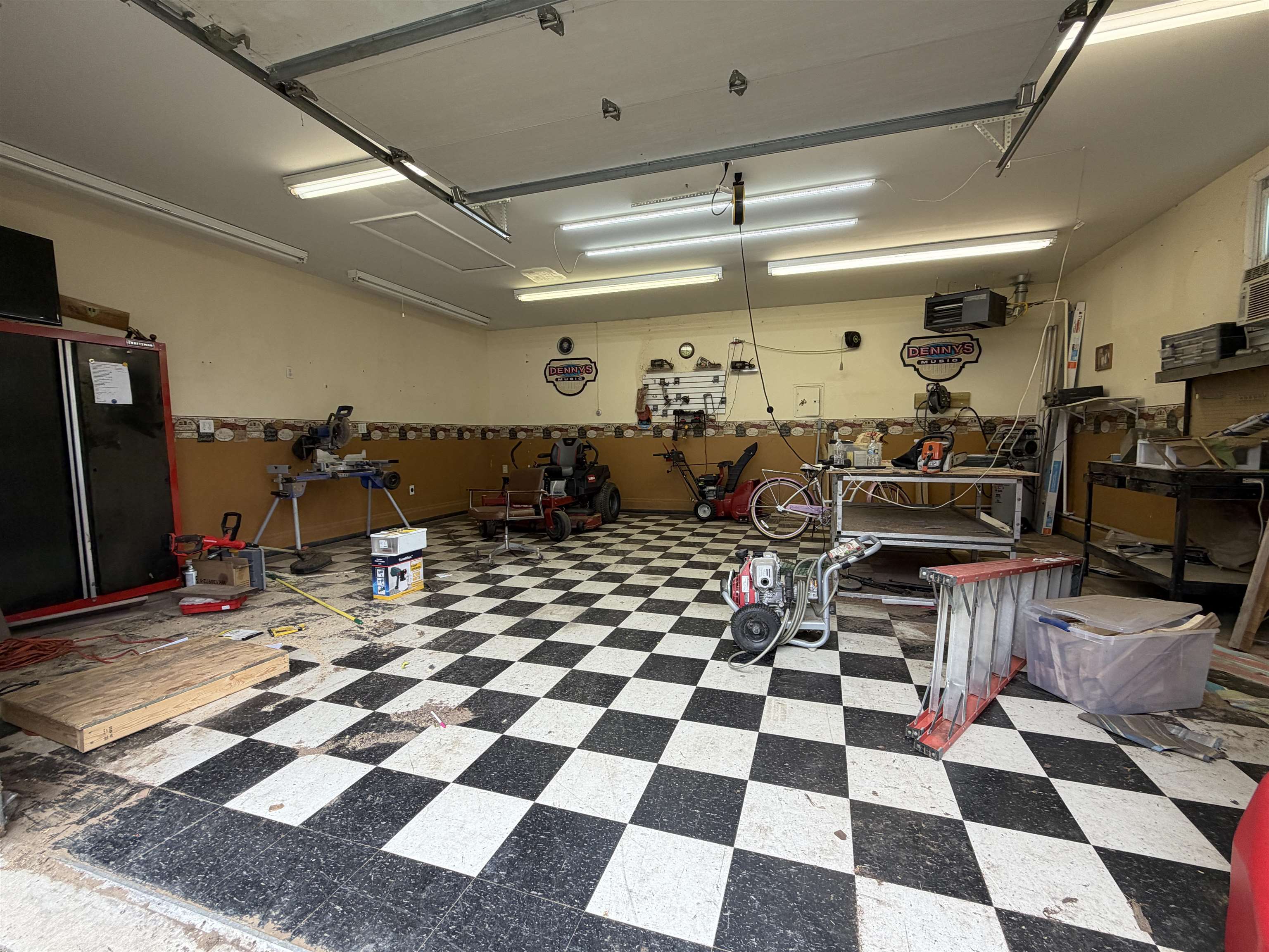 Spacious garage featuring checkered flooring, fluorescent lighting, and a wall-mounted heater
